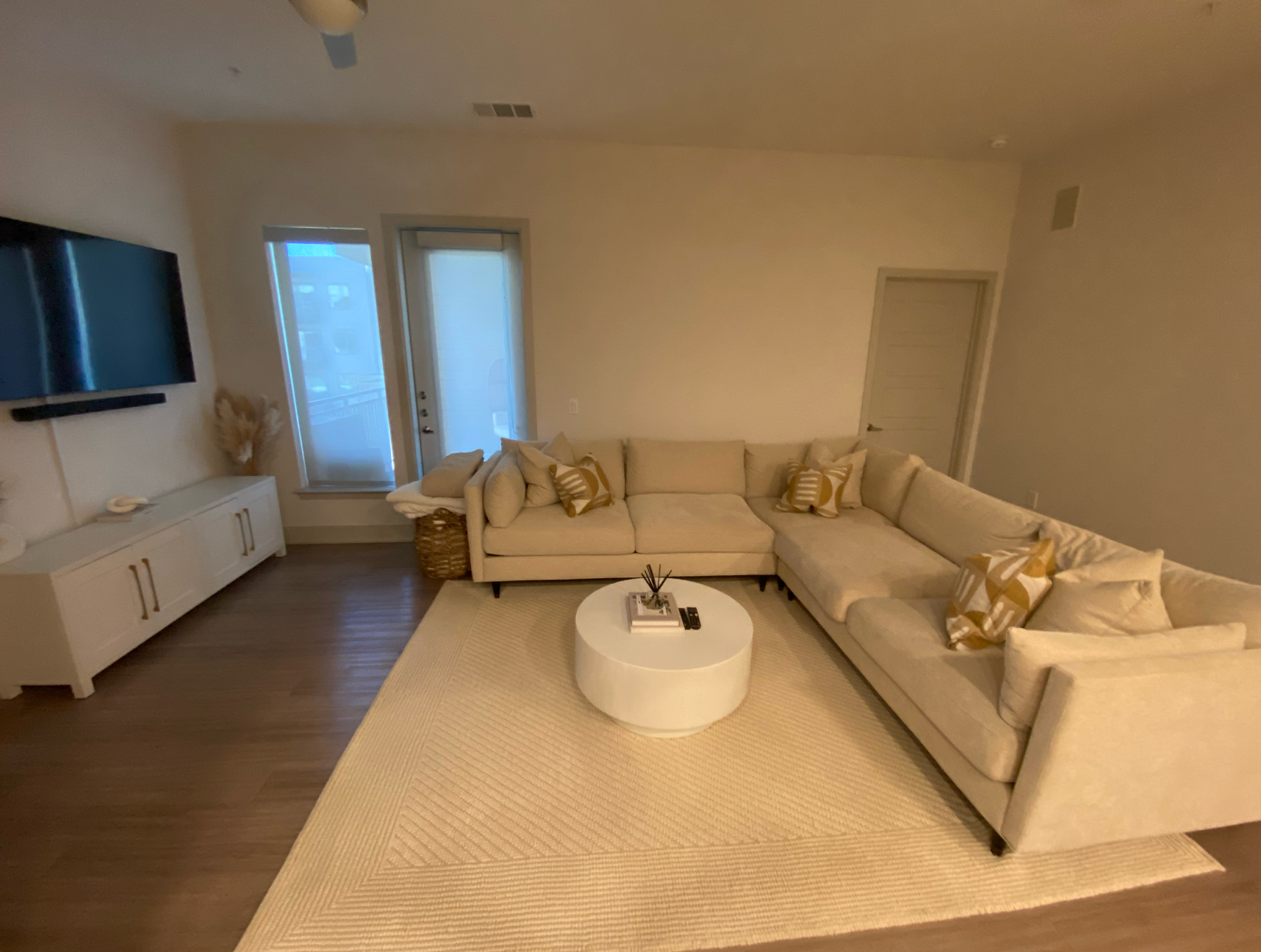 A living room with a large sectional couch and a round coffee table.