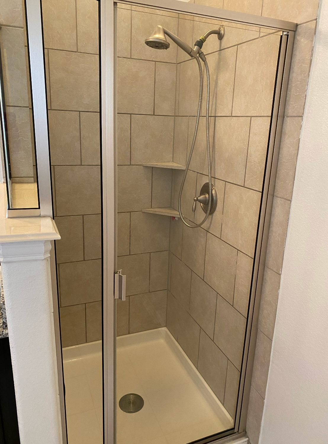 A shower stall with a glass door and a shower head in a bathroom.
