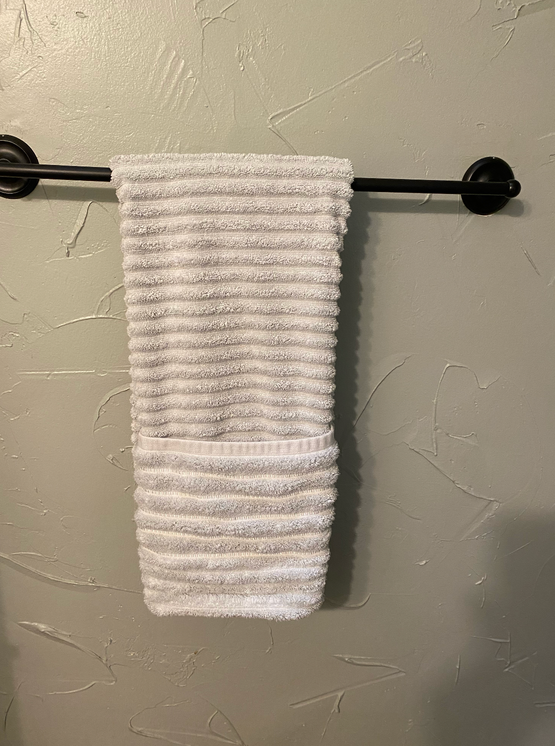 A white towel is hanging on a black towel rack.