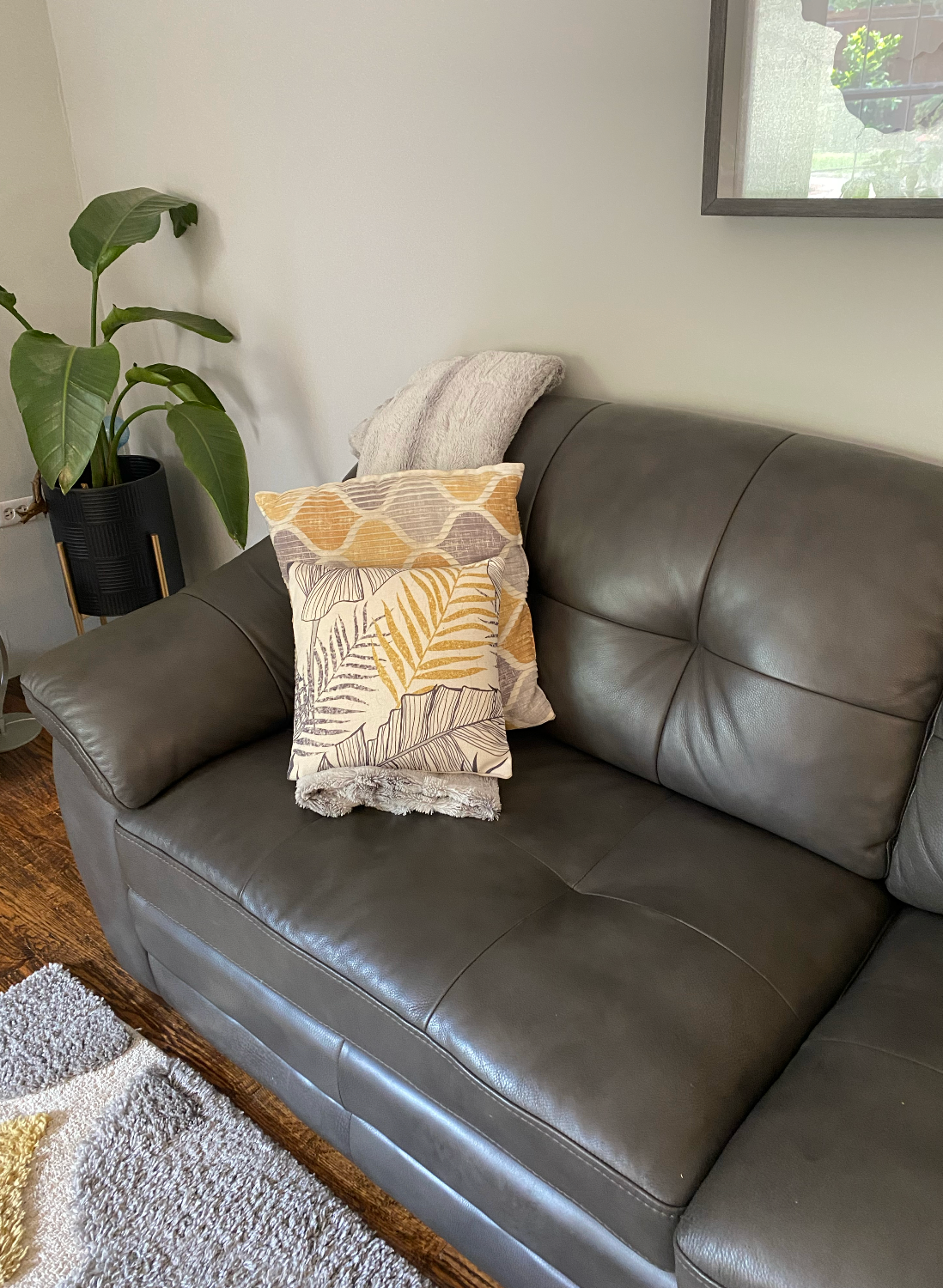 A gray leather couch with two pillows on it in a living room.