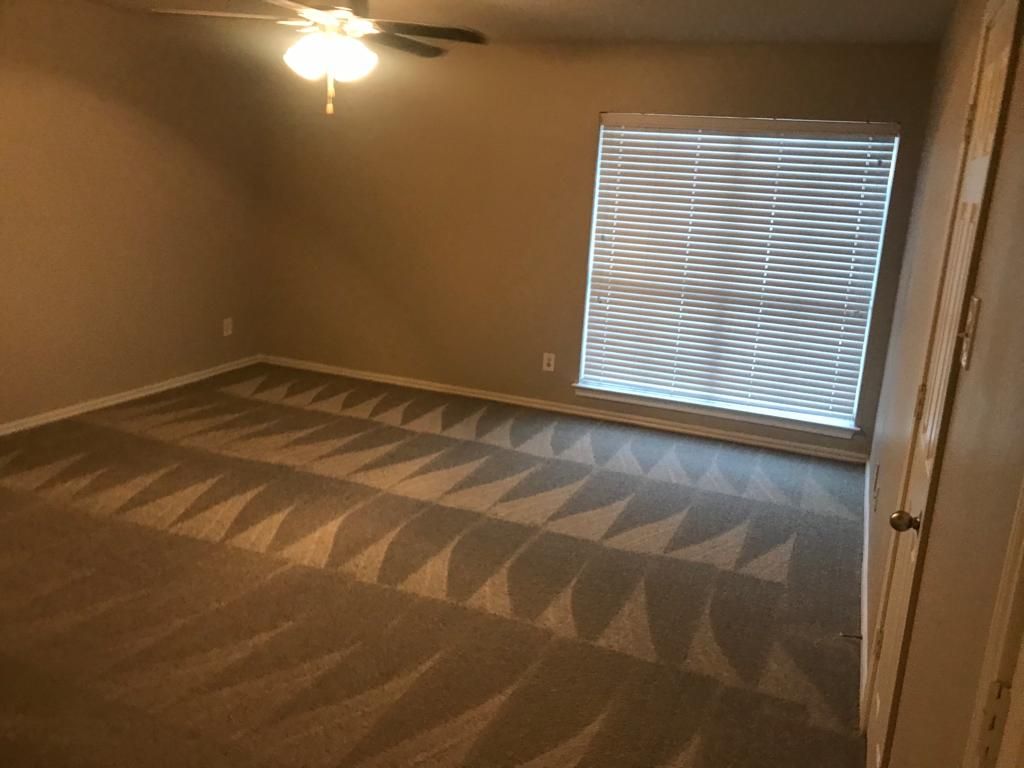 An empty bedroom with a ceiling fan and blinds.