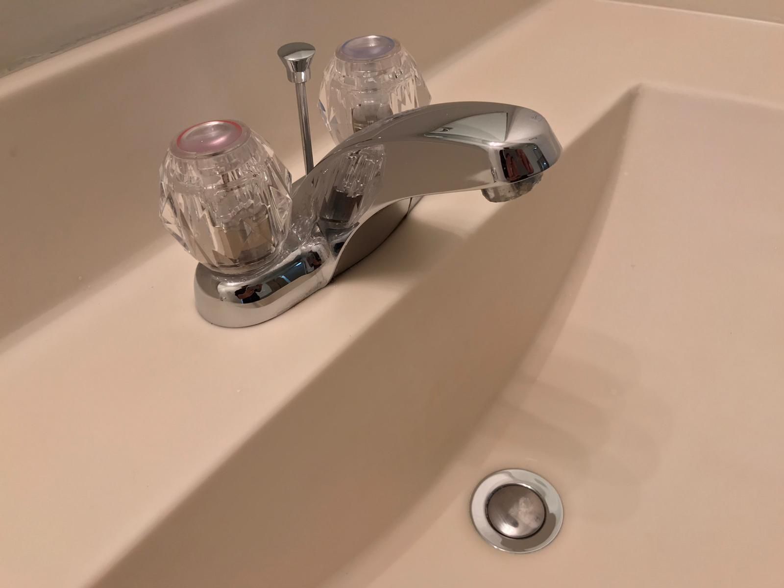 A bathroom sink with a chrome faucet and clear handles