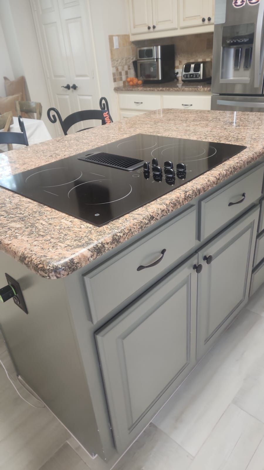 A kitchen island with a stove top oven and granite counter tops.