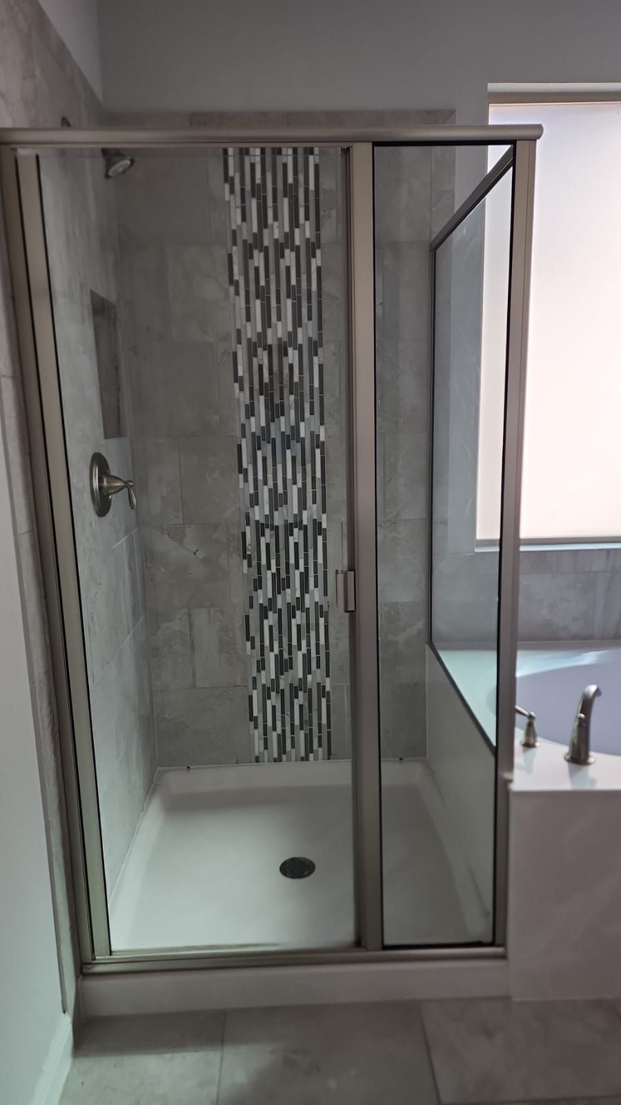 A bathroom with a walk in shower and a window.