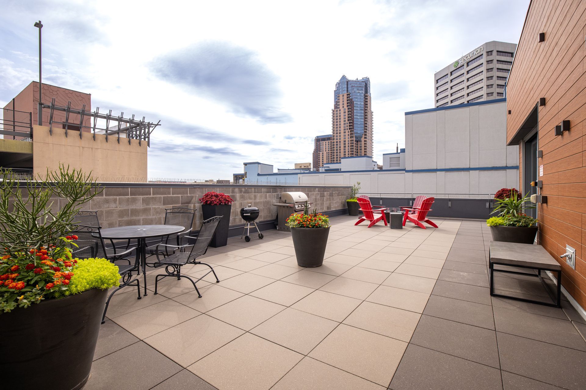 Rooftop patio with city views, including chairs, tables, a grill, and planters at R7 Lofts in St. Paul, MN.
