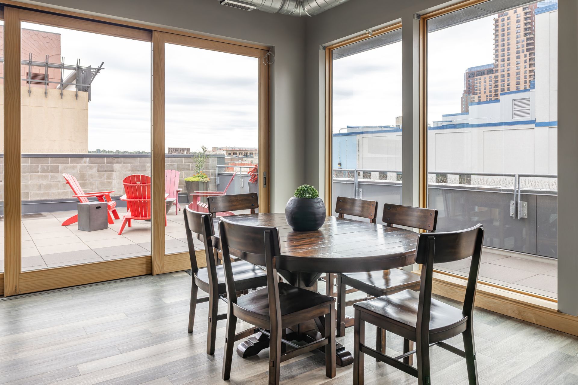 Dining table with chairs near a patio door, overlooking a rooftop with red chairs at R7 Lofts in St. Paul, MN.
