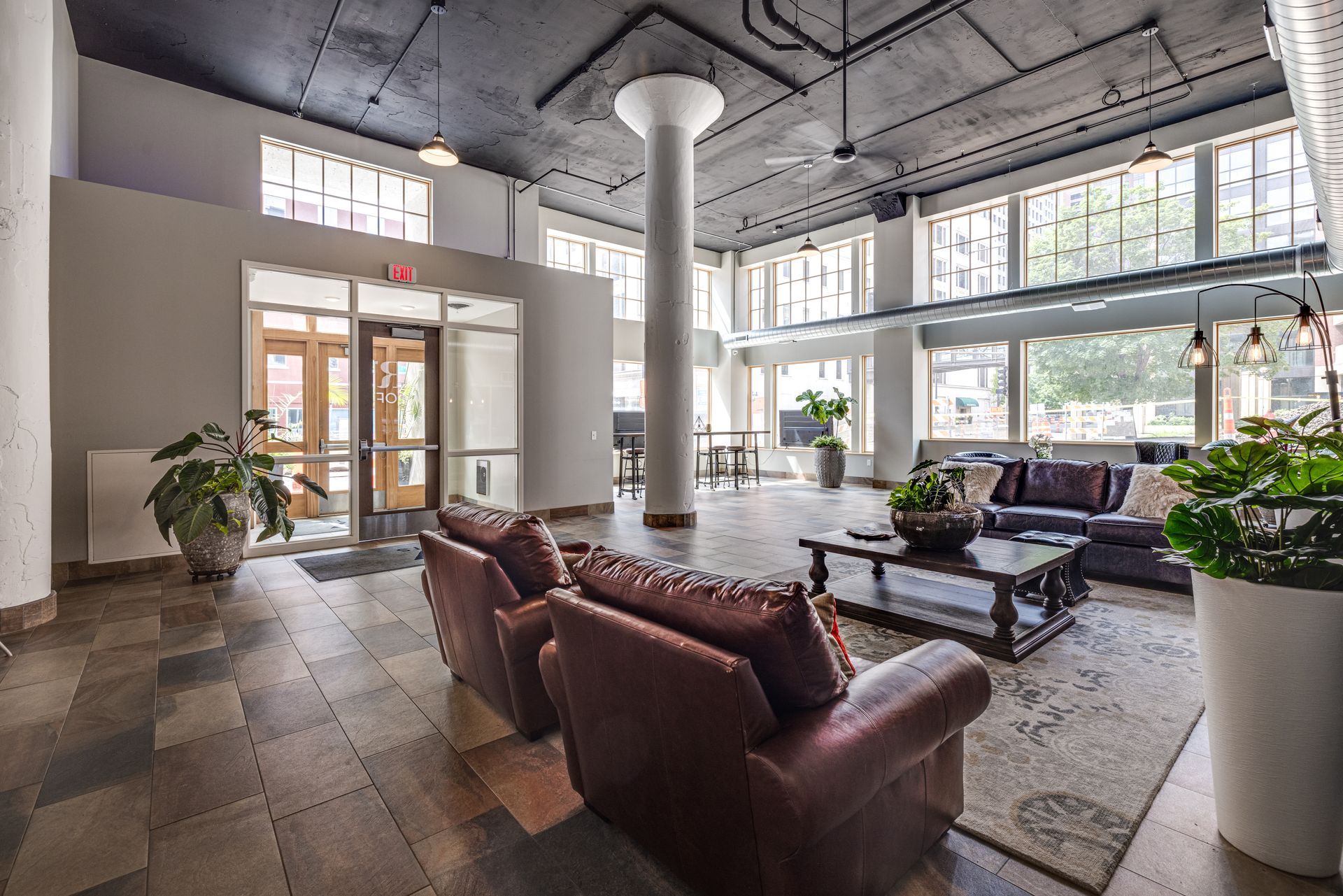 Lobby with leather chairs, large windows, and a central pillar at R7 Lofts in St. Paul, MN.