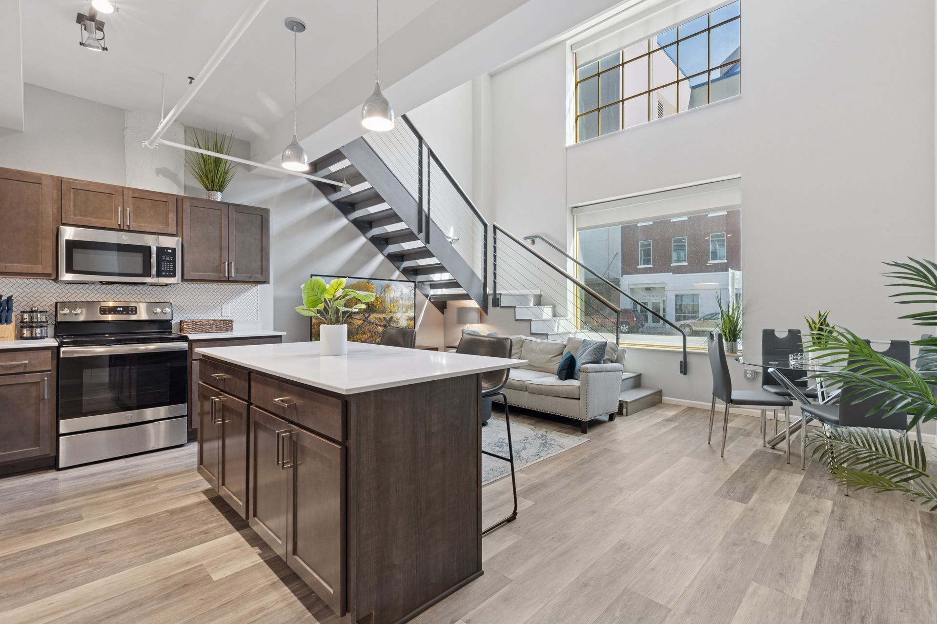 Modern loft interior with kitchen island, stairs to upper level, and large windows at R7 Lofts in St. Paul, MN.