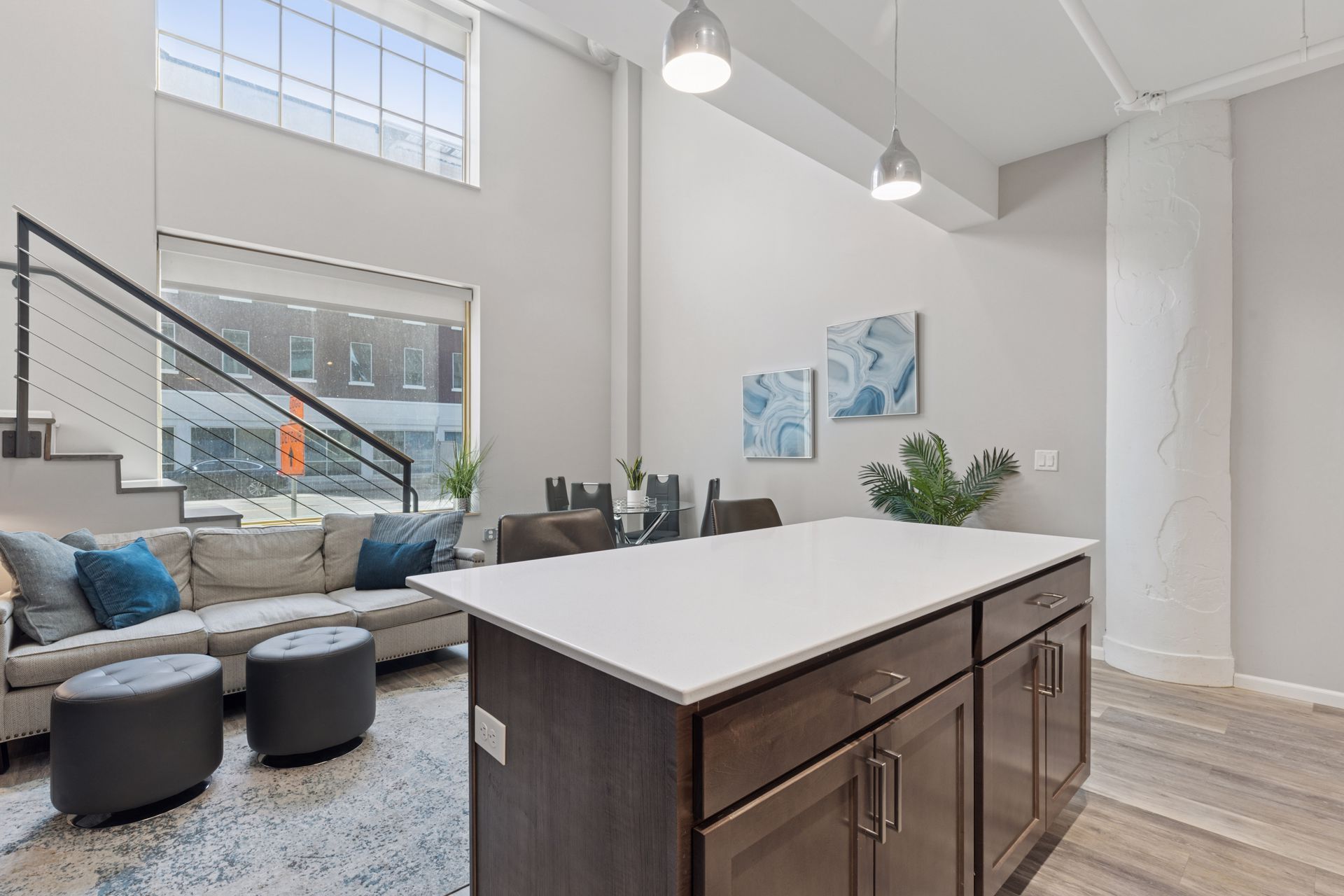 Open-concept loft with a kitchen island, sofa, and dining area. Neutral colors and large windows at R7 Lofts in St. Paul, MN.