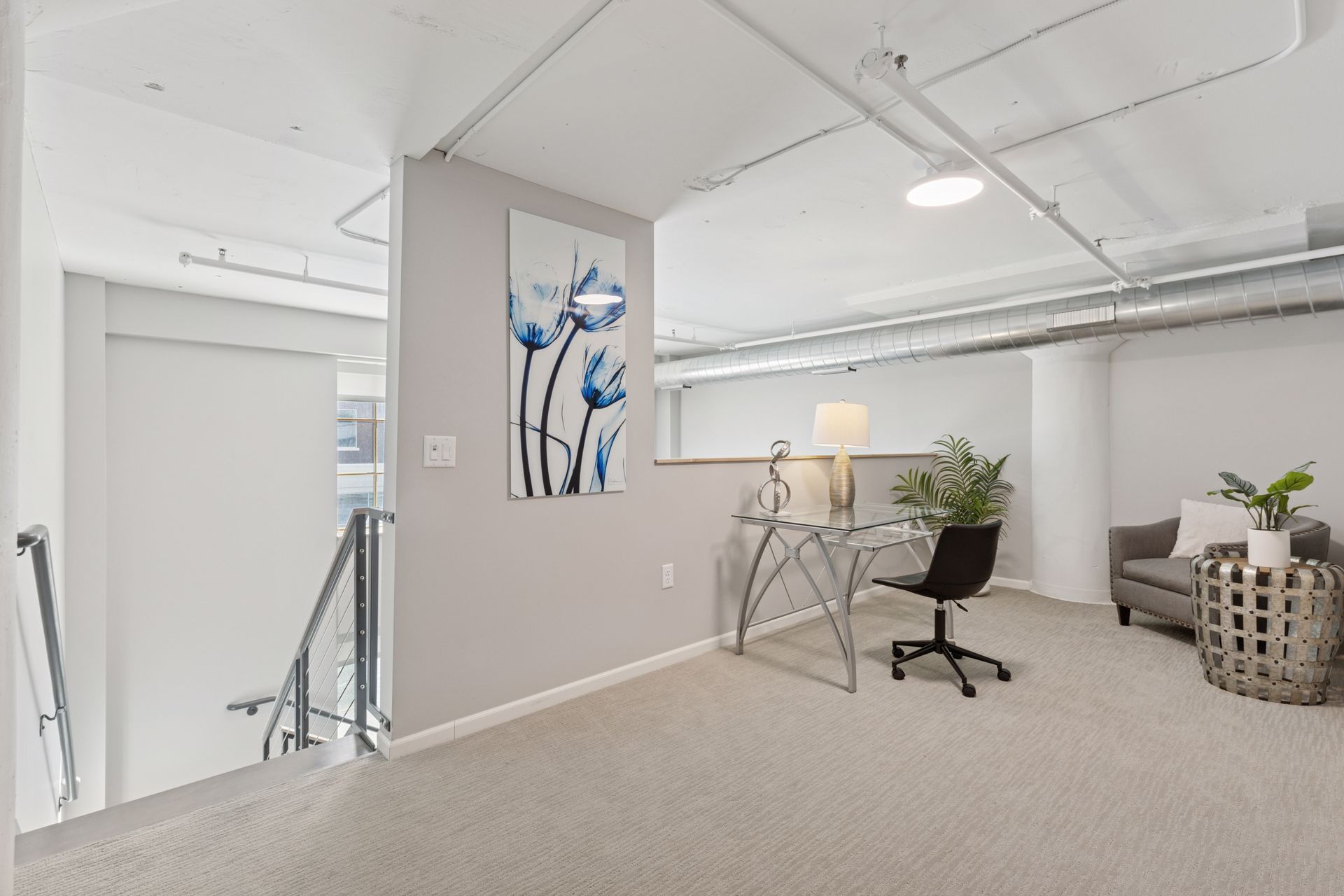 Loft space with desk, chair, painting, sofa, and side table. Neutral colors with industrial accents at R7 Lofts in St. Paul, MN.
