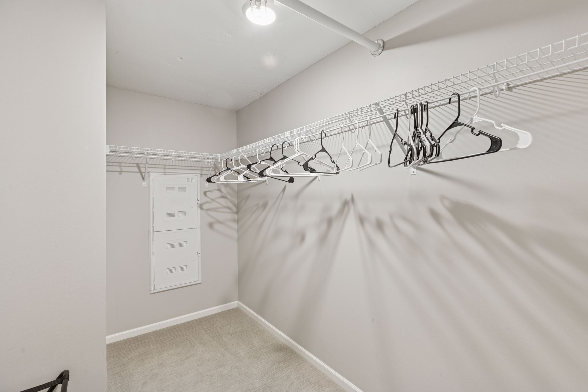 Empty walk-in closet with wire shelving and hangers against neutral gray walls at R7 Lofts in St. Paul, MN.