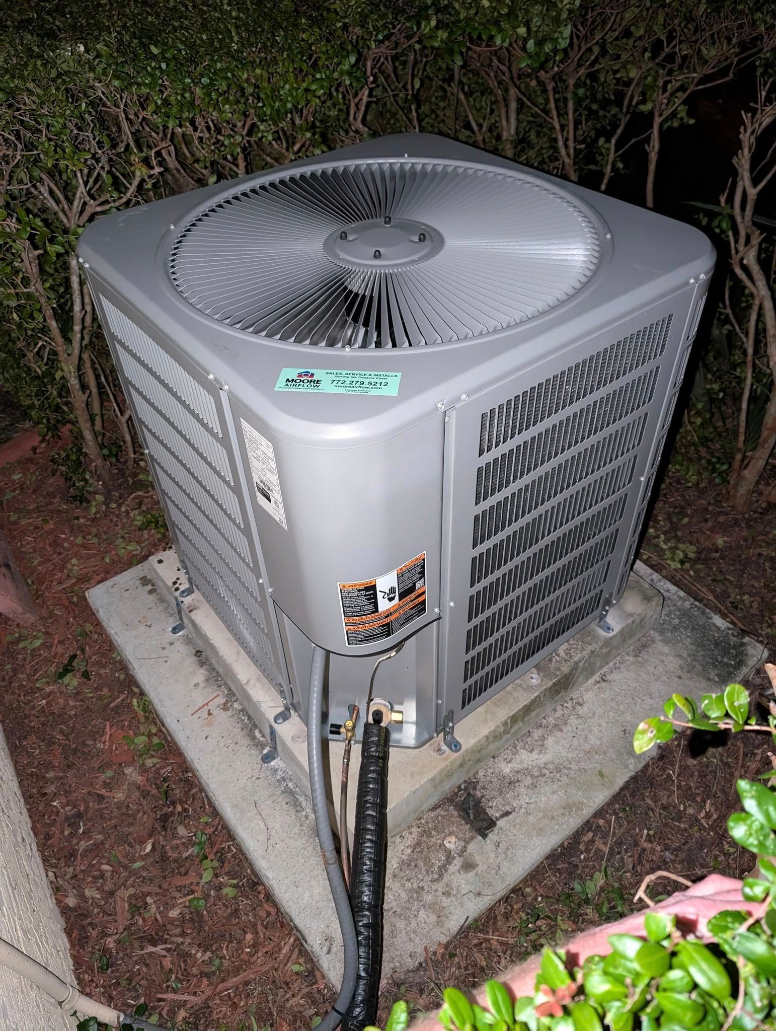 A large air conditioner is sitting on top of a concrete block.