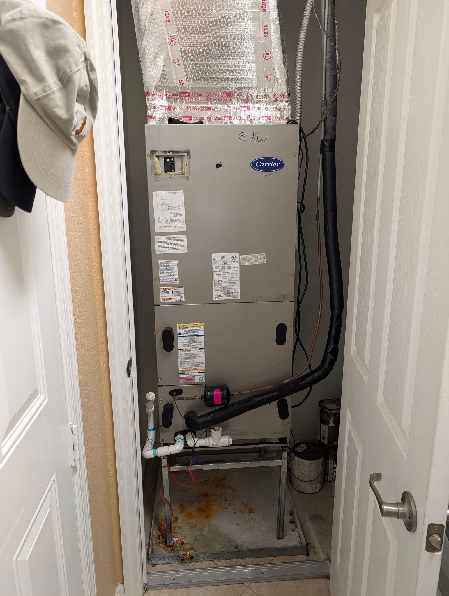 An air conditioner is sitting in a closet next to a door.