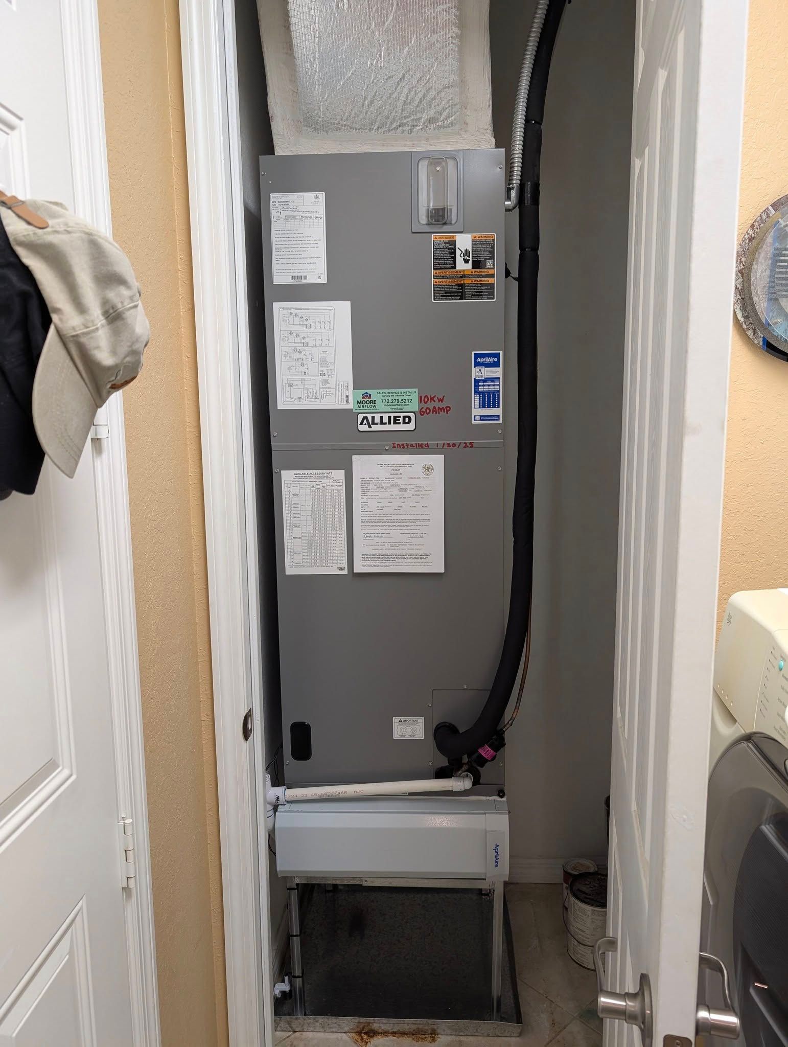 An air conditioner is sitting in a closet next to a washing machine.