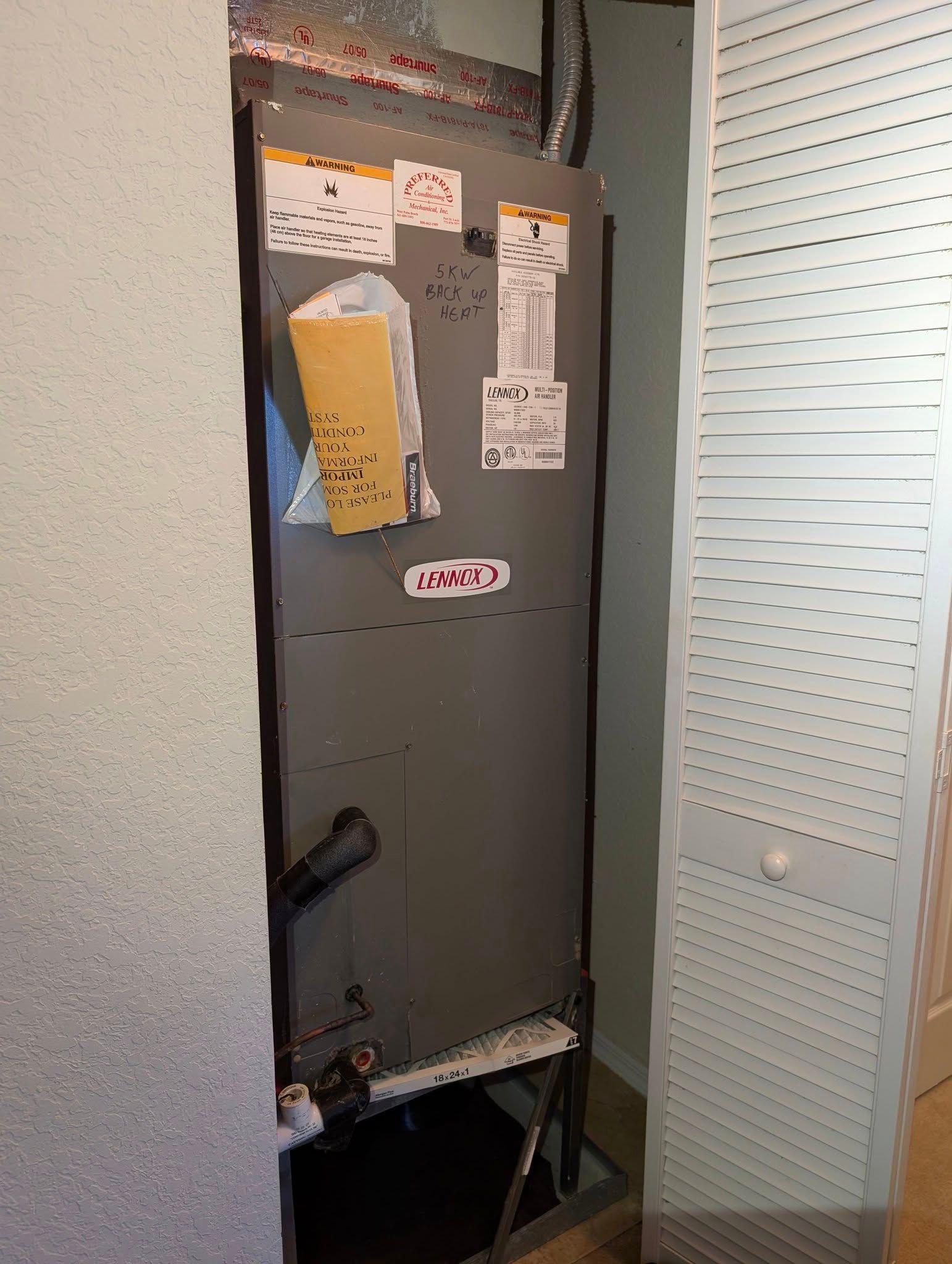 An air conditioner is sitting in a closet next to a wall.