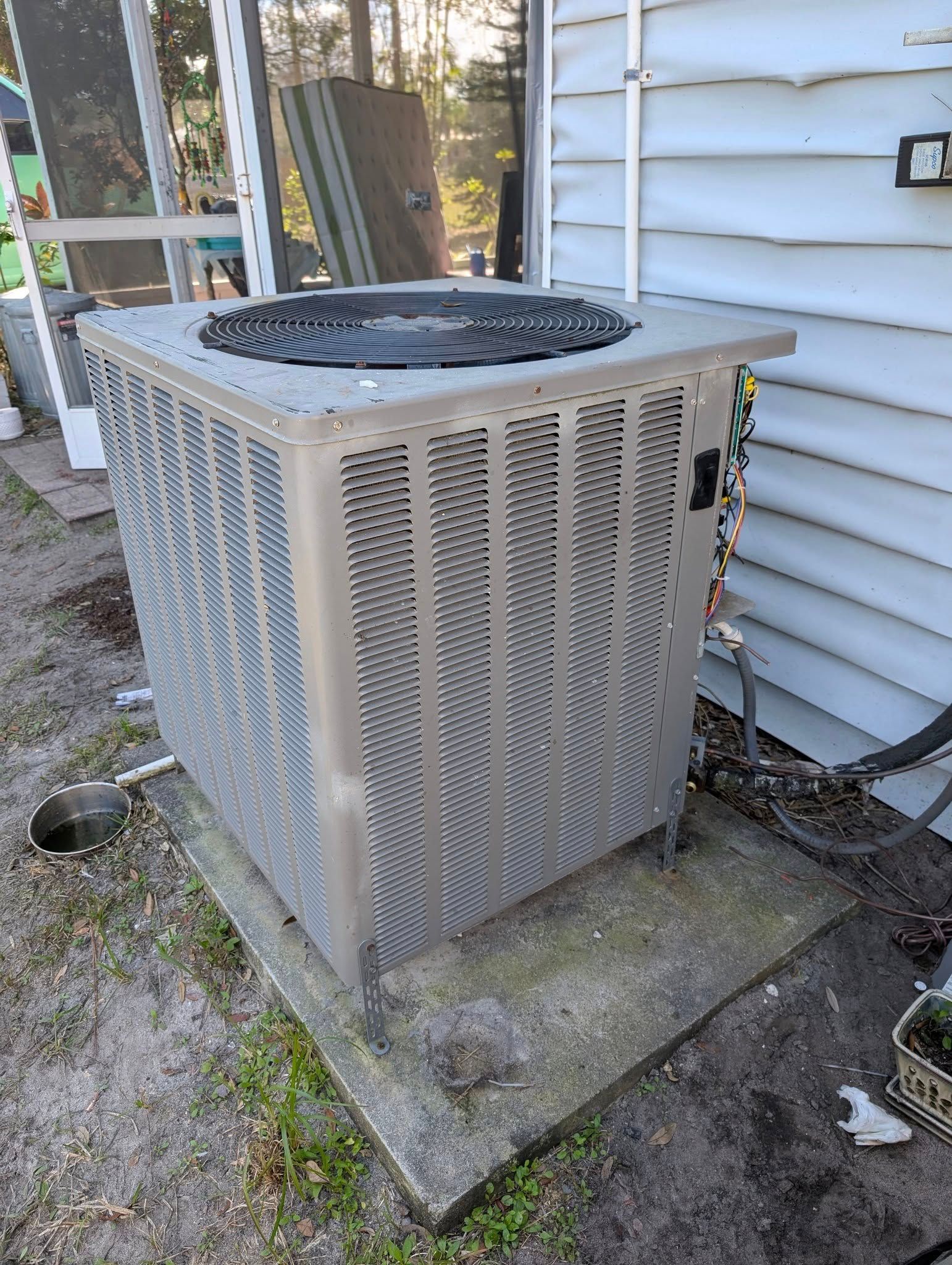 An air conditioner is sitting on the side of a house.