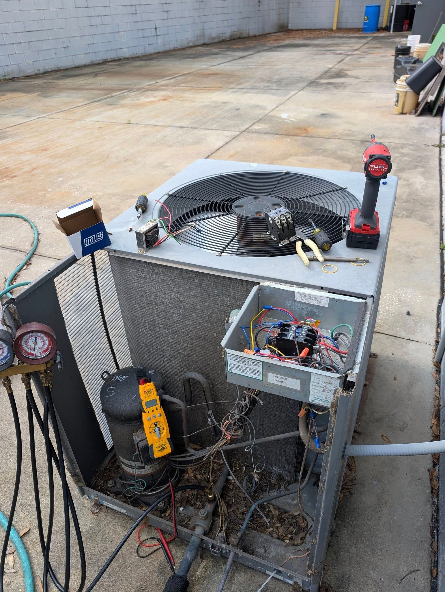 An air conditioner is being repaired in a parking lot.