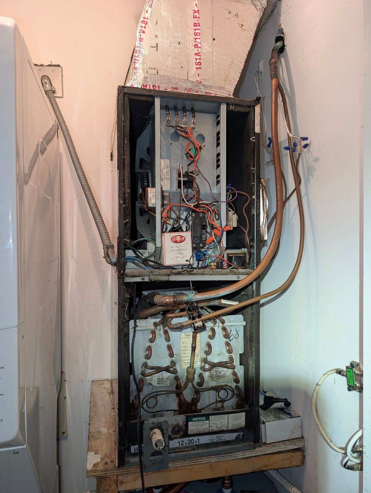 A broken air conditioner is sitting in a corner of a room.