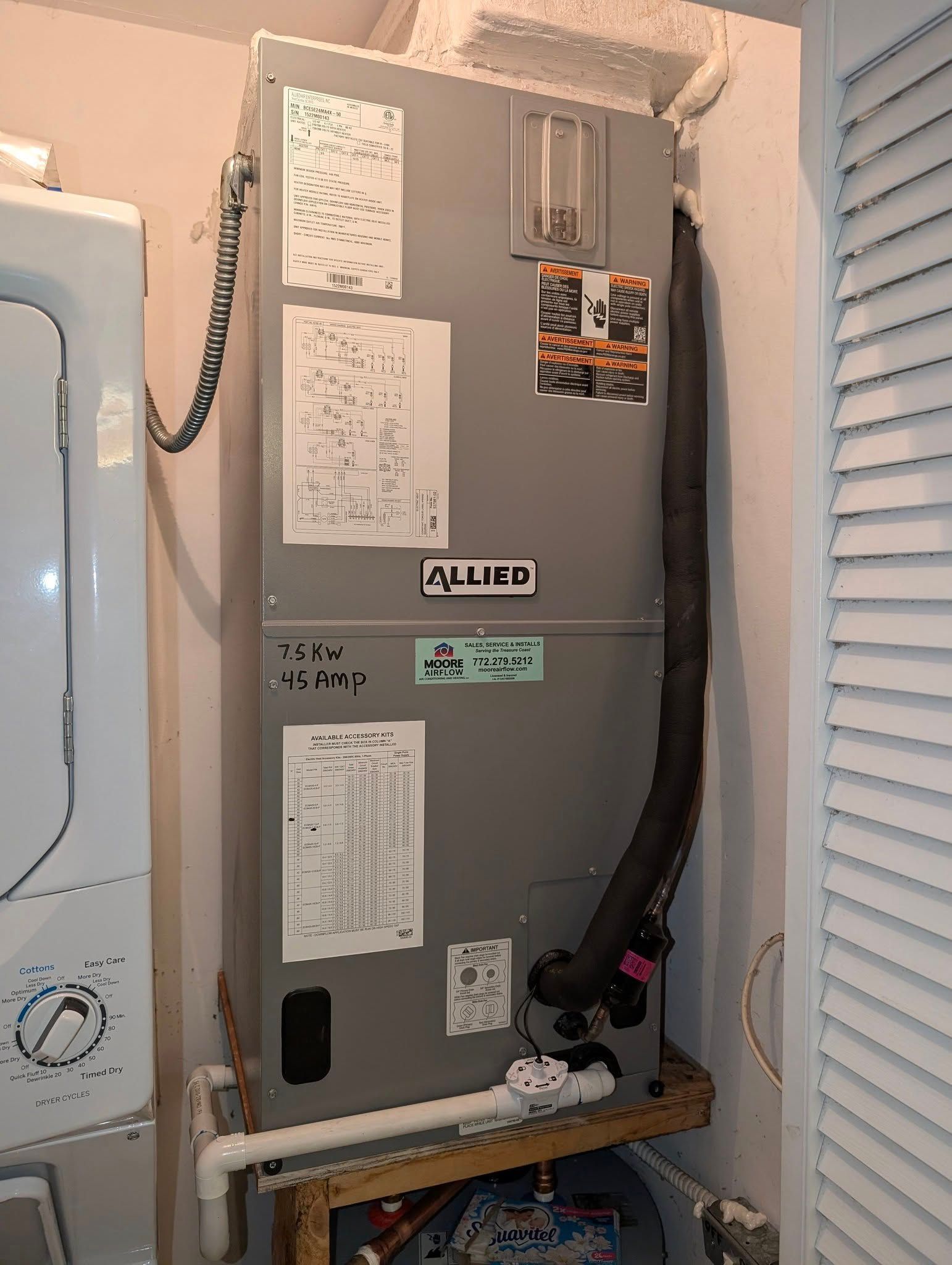 An air conditioner is sitting in a laundry room next to a washer and dryer.