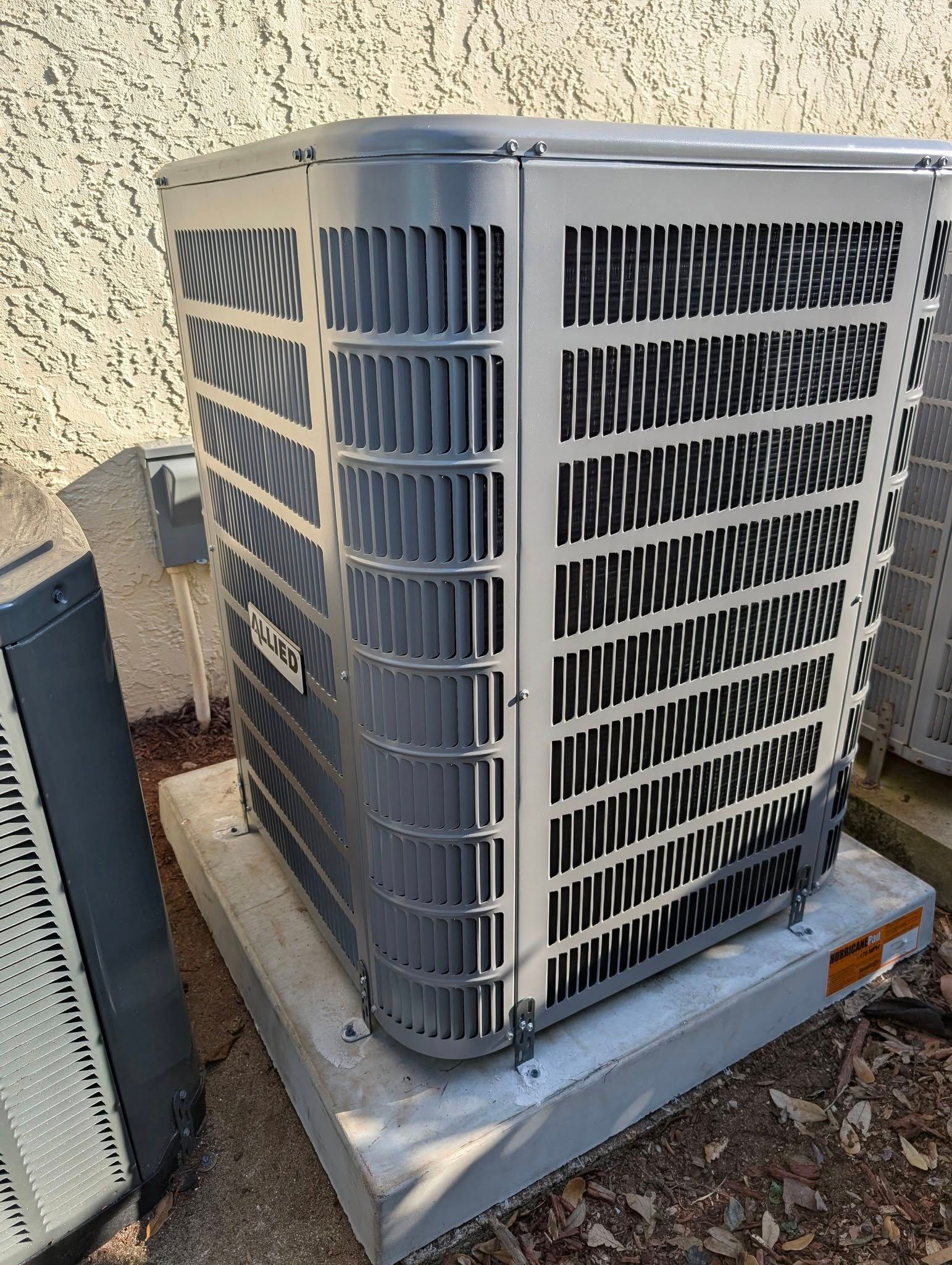 A large air conditioner is sitting on top of a concrete block.