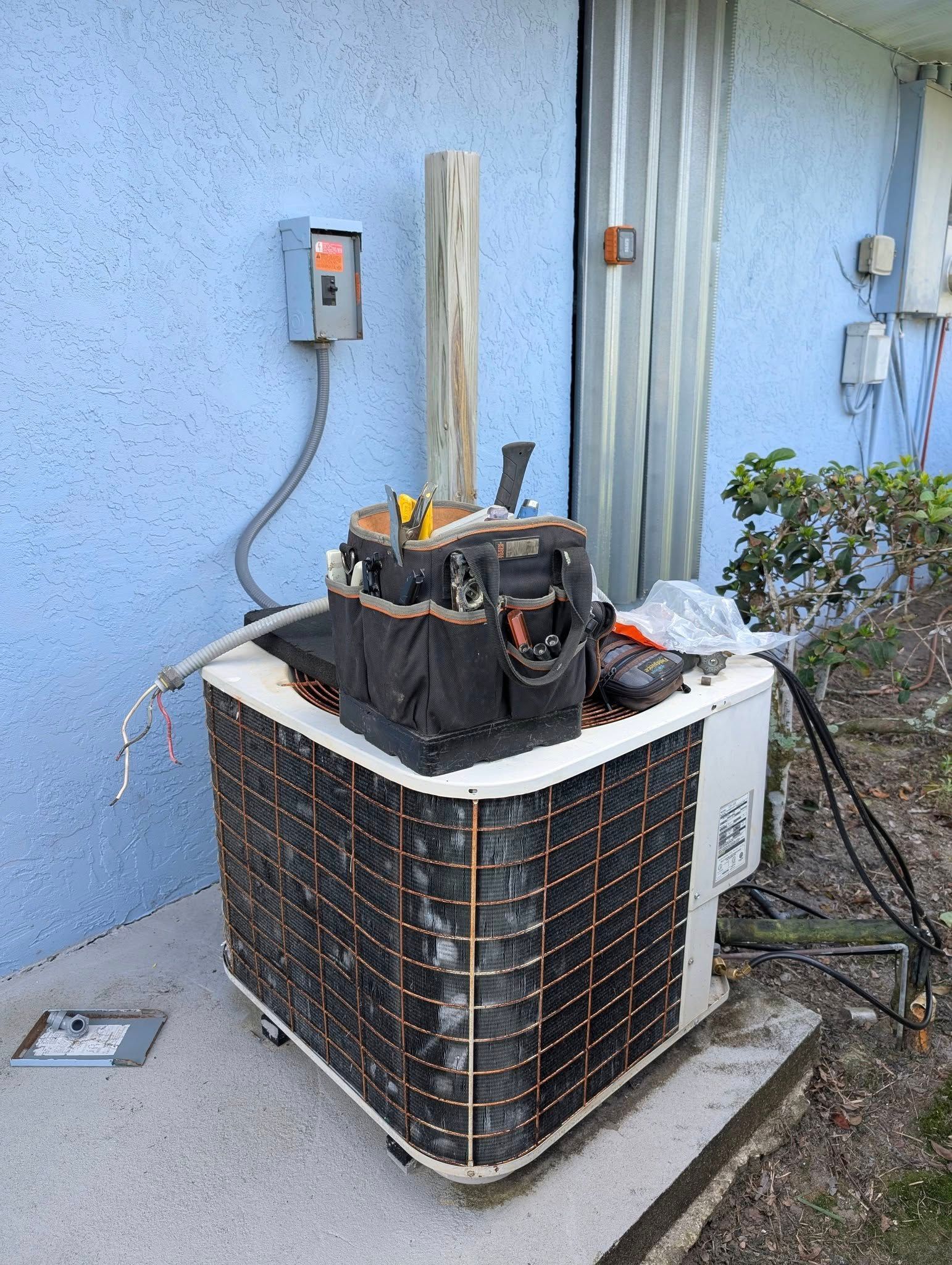 A broken air conditioner is sitting on the side of a building.