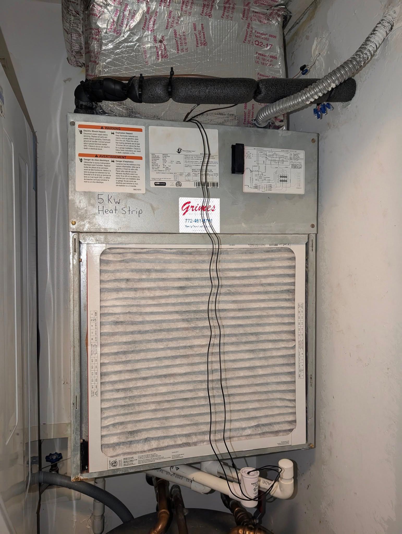 A dirty air conditioner is hanging on a wall in a room.