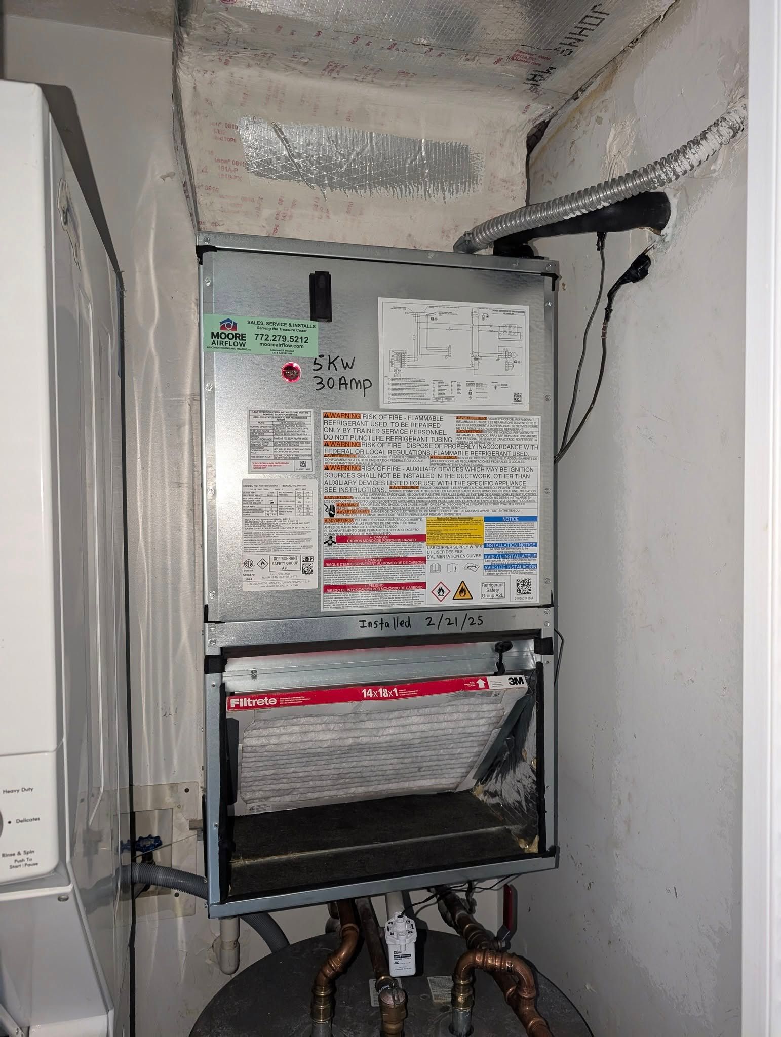 A heater is hanging on a wall next to a washer and dryer.