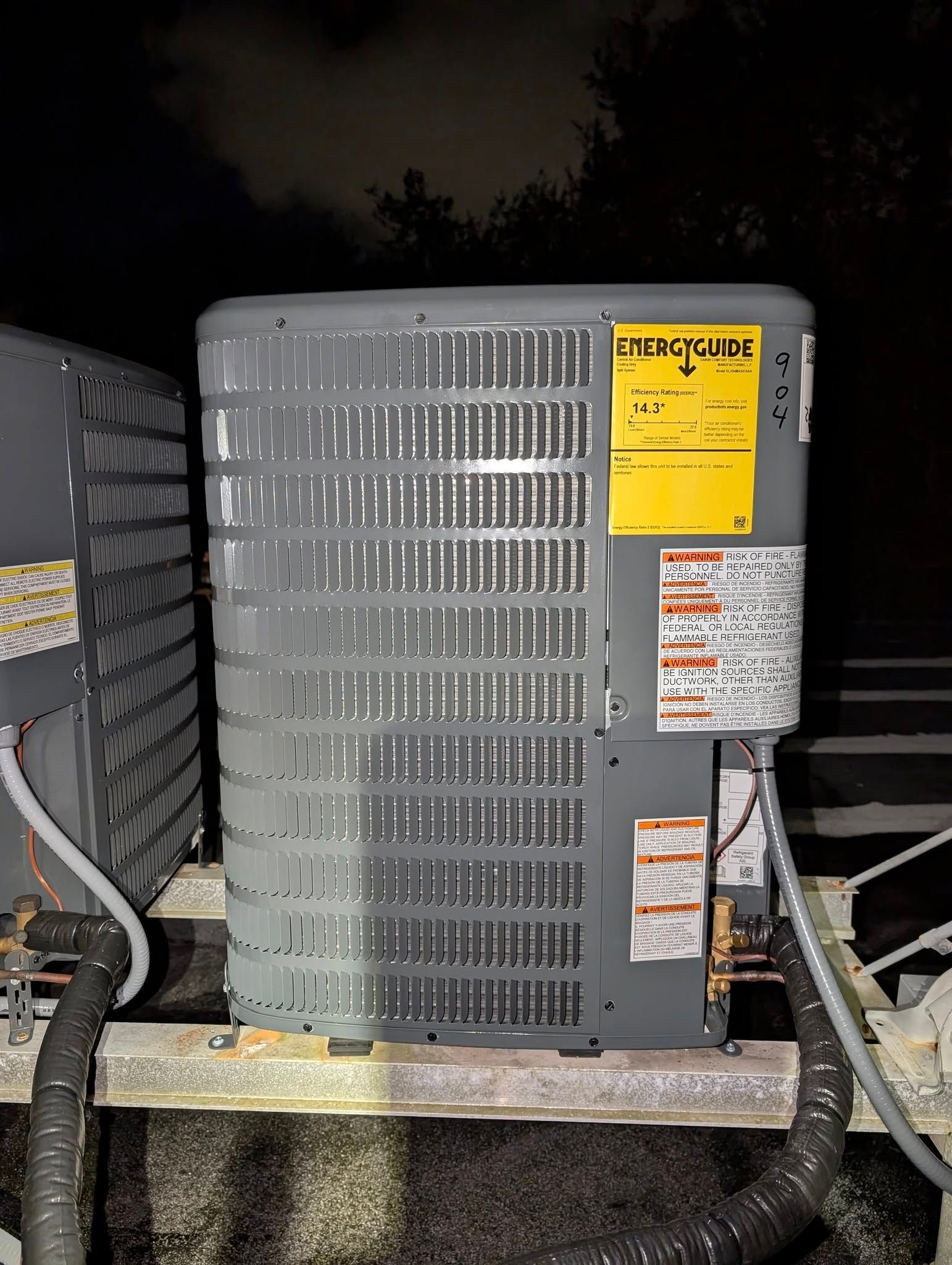 A large air conditioner is sitting on top of a roof at night.