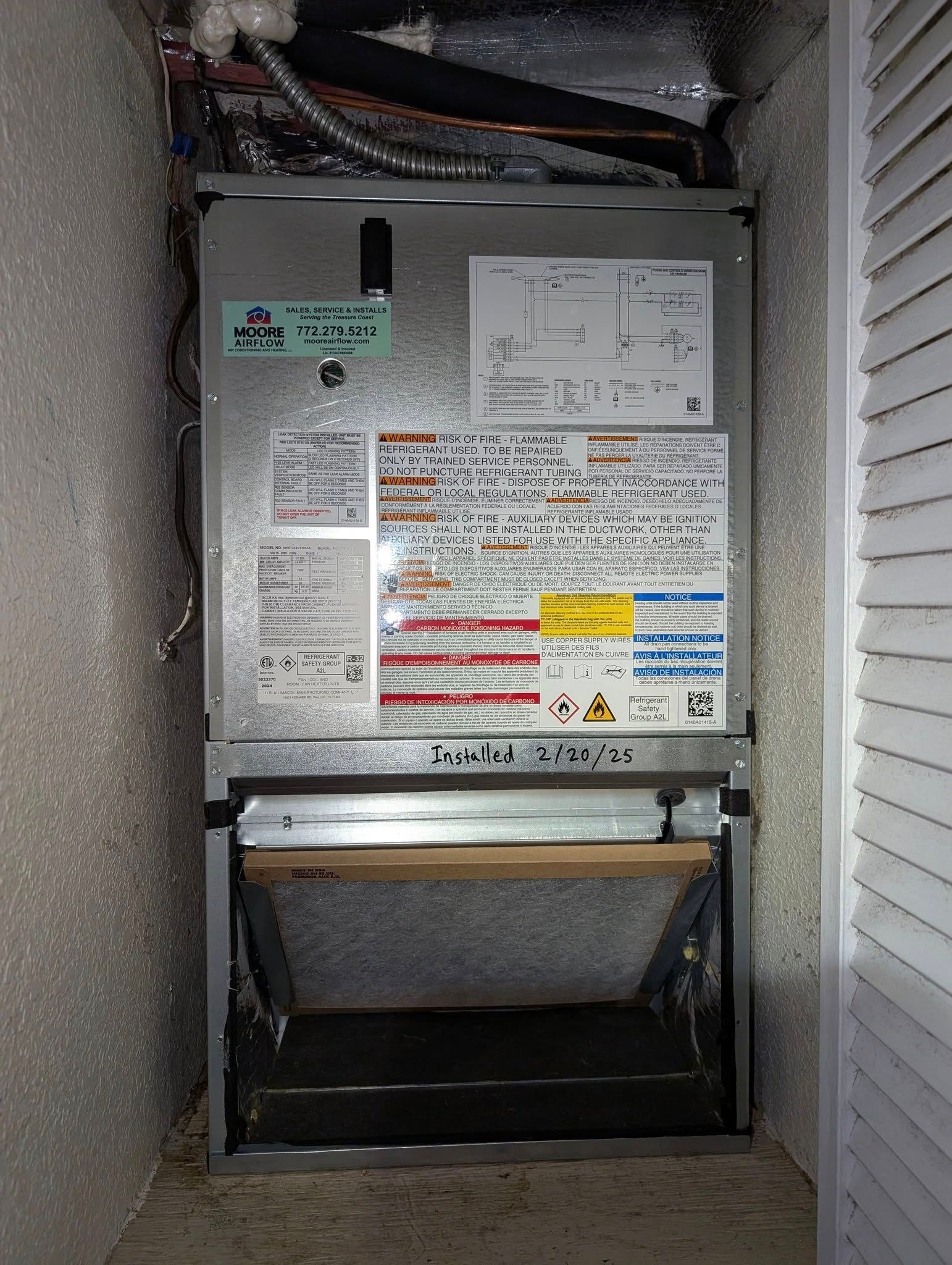 An air conditioner is sitting in a corner of a room next to a wall.