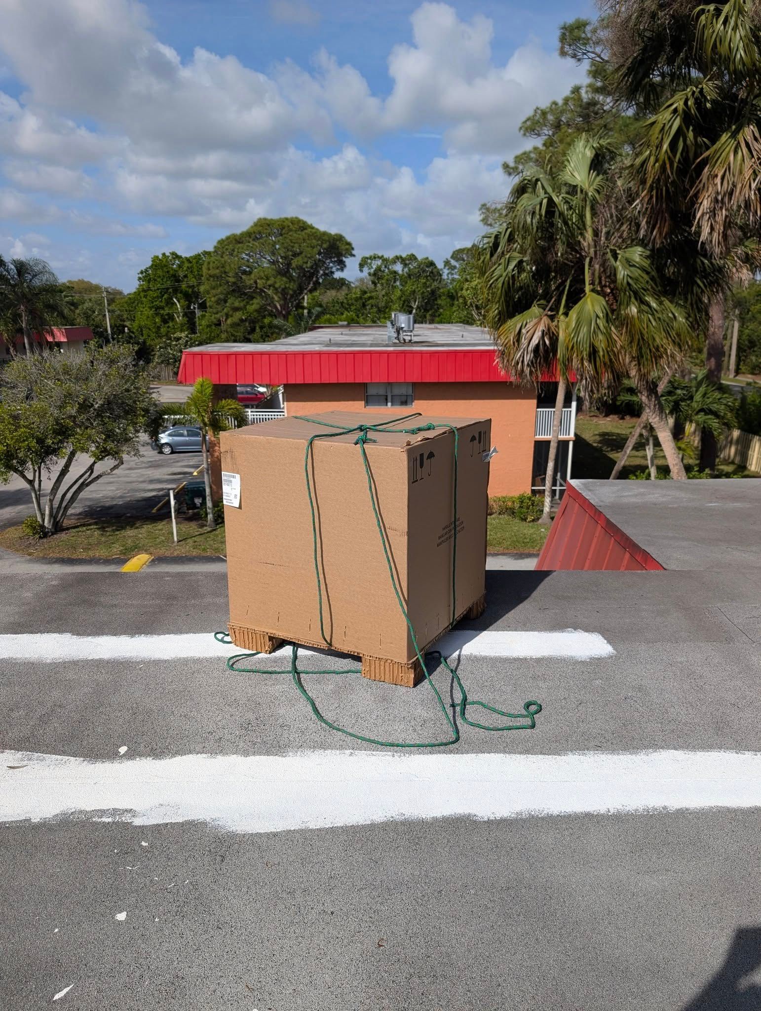 A cardboard box is tied to a pallet in a parking lot.