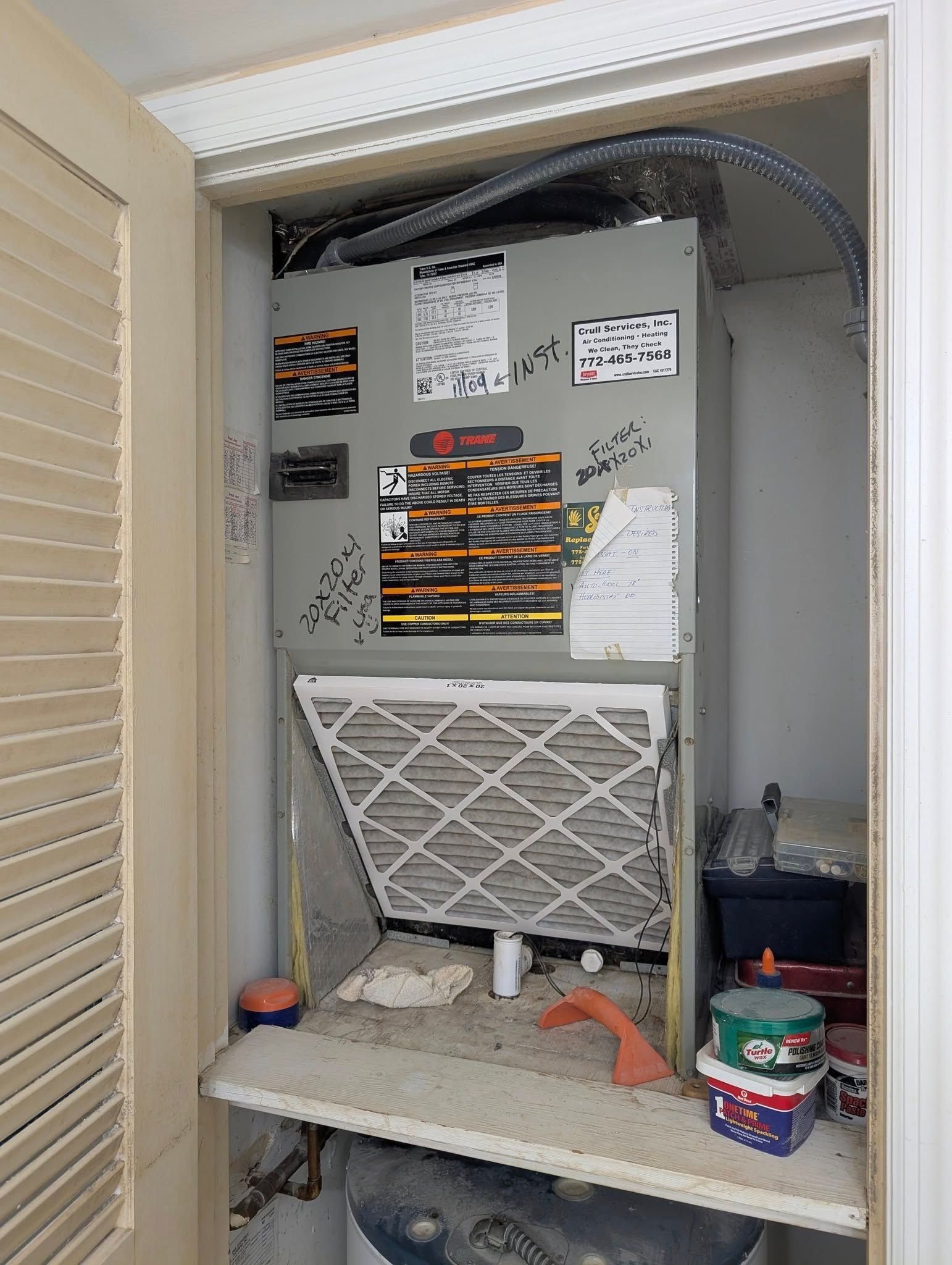 An air conditioner is sitting inside of a closet next to a shelf.