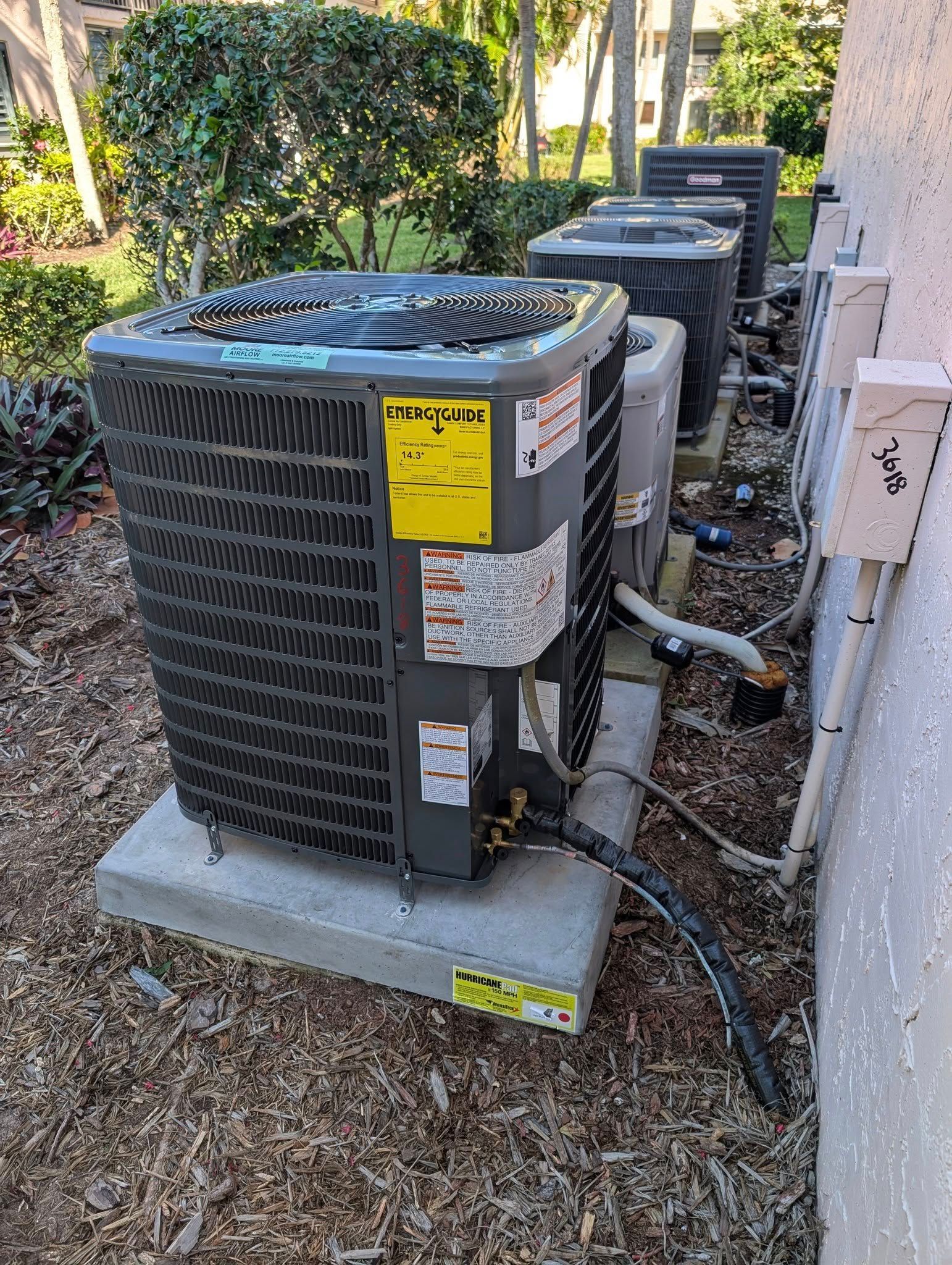 A group of air conditioners are sitting outside of a building.