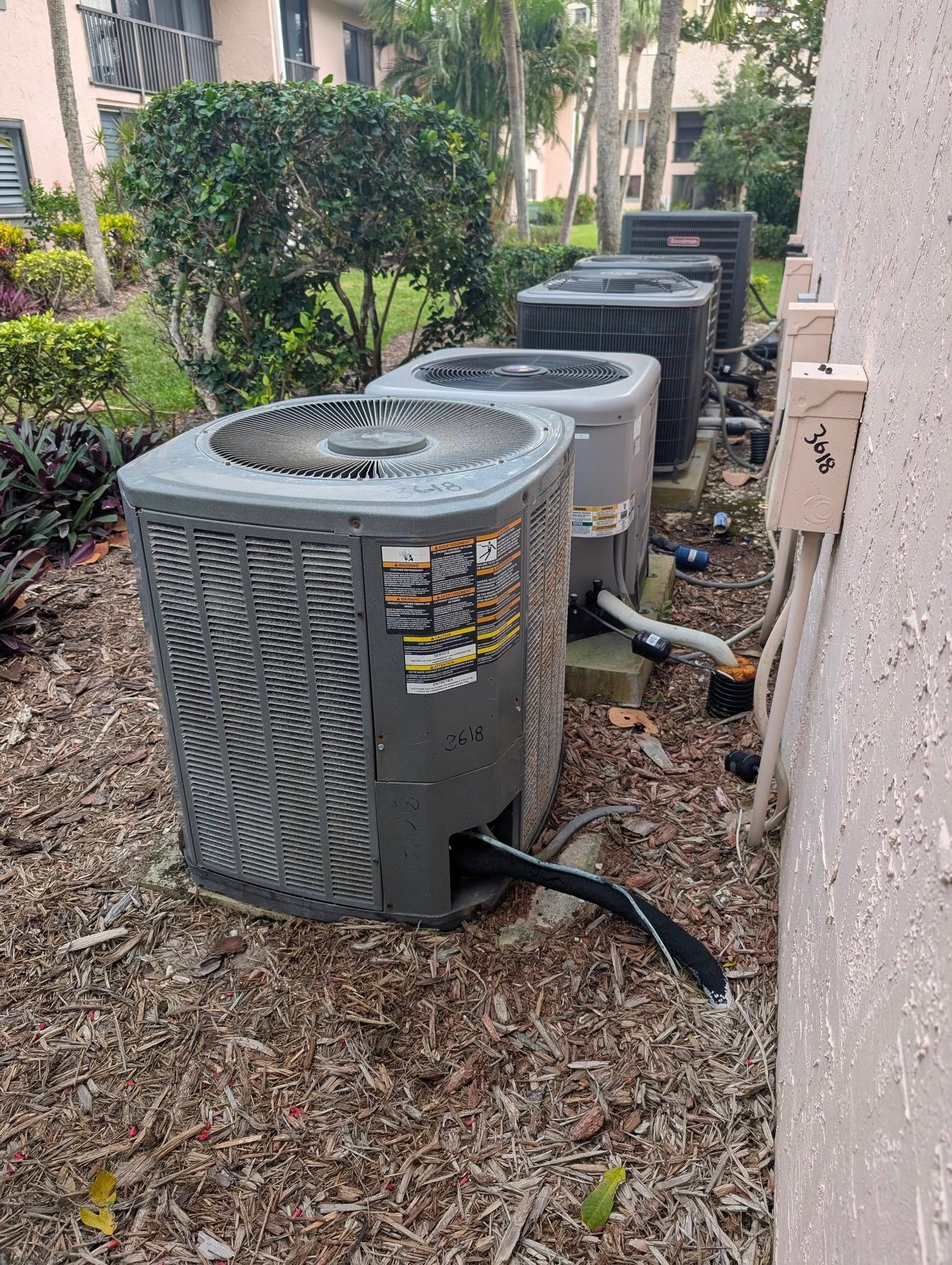 A row of air conditioners are sitting next to each other on the side of a building.