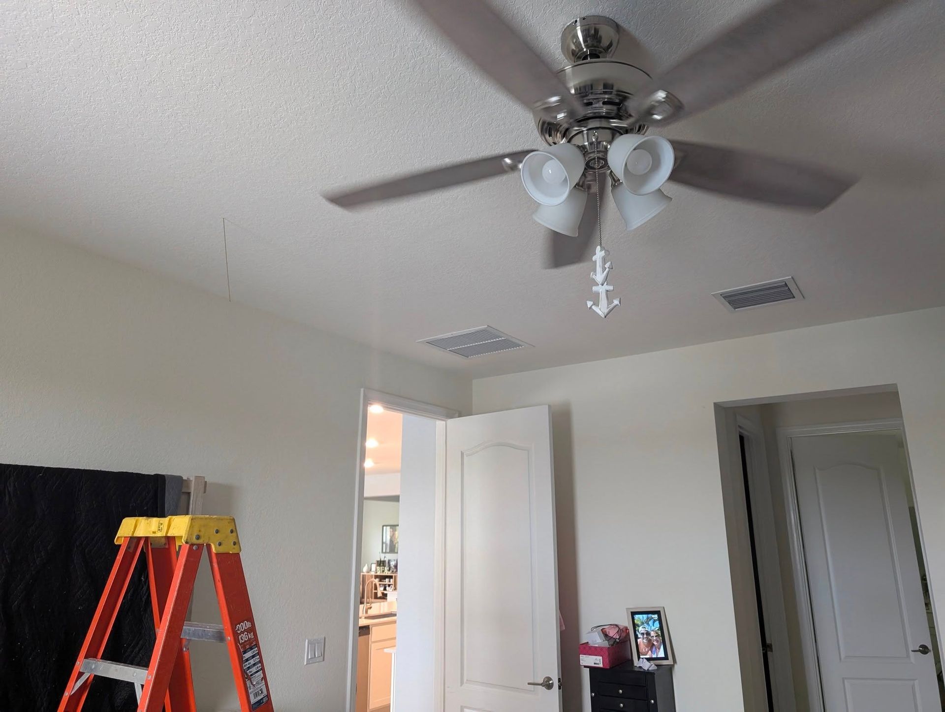 A room with a ceiling fan and a ladder