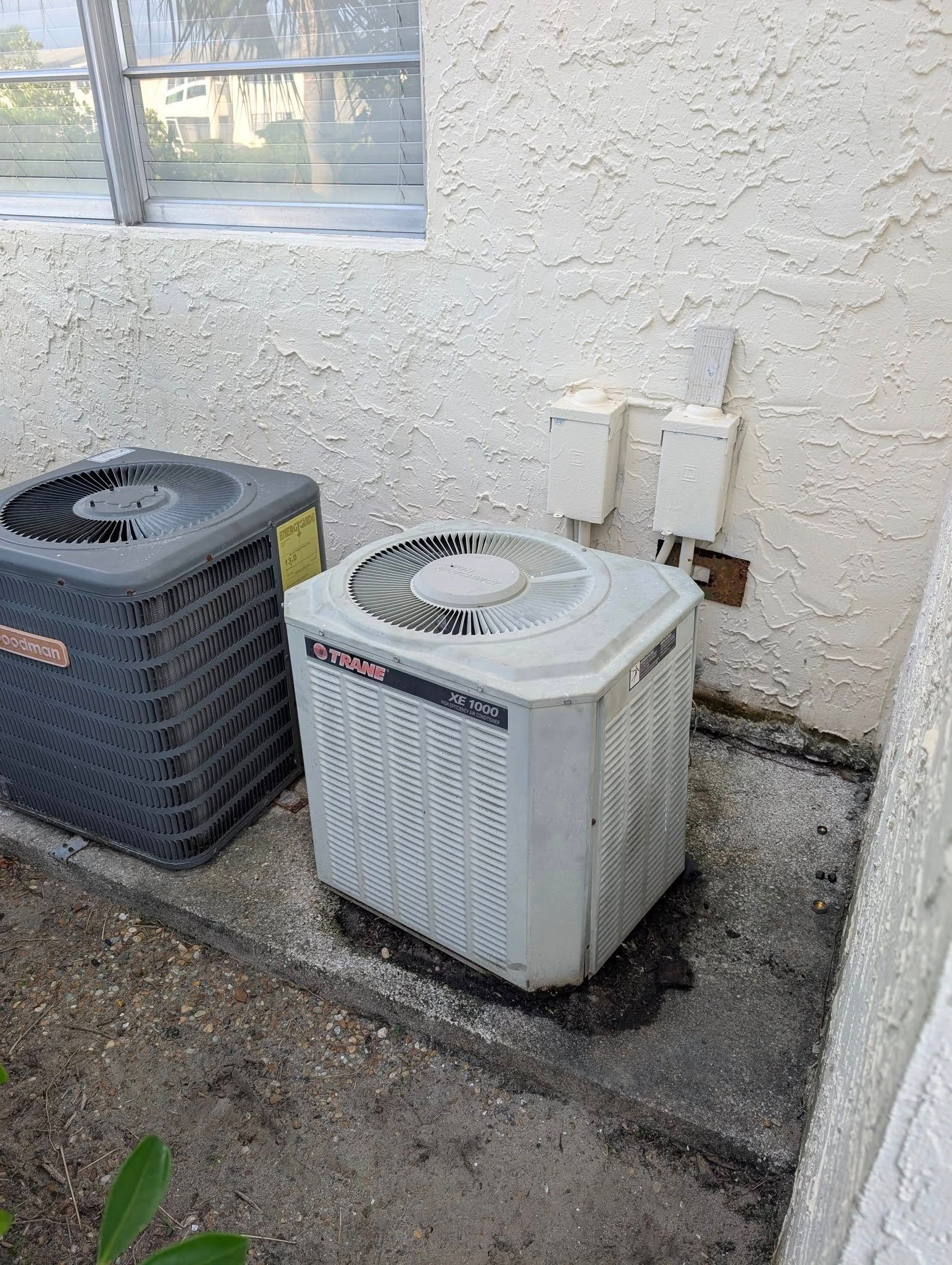 An air conditioner is sitting on the side of a building next to a window.