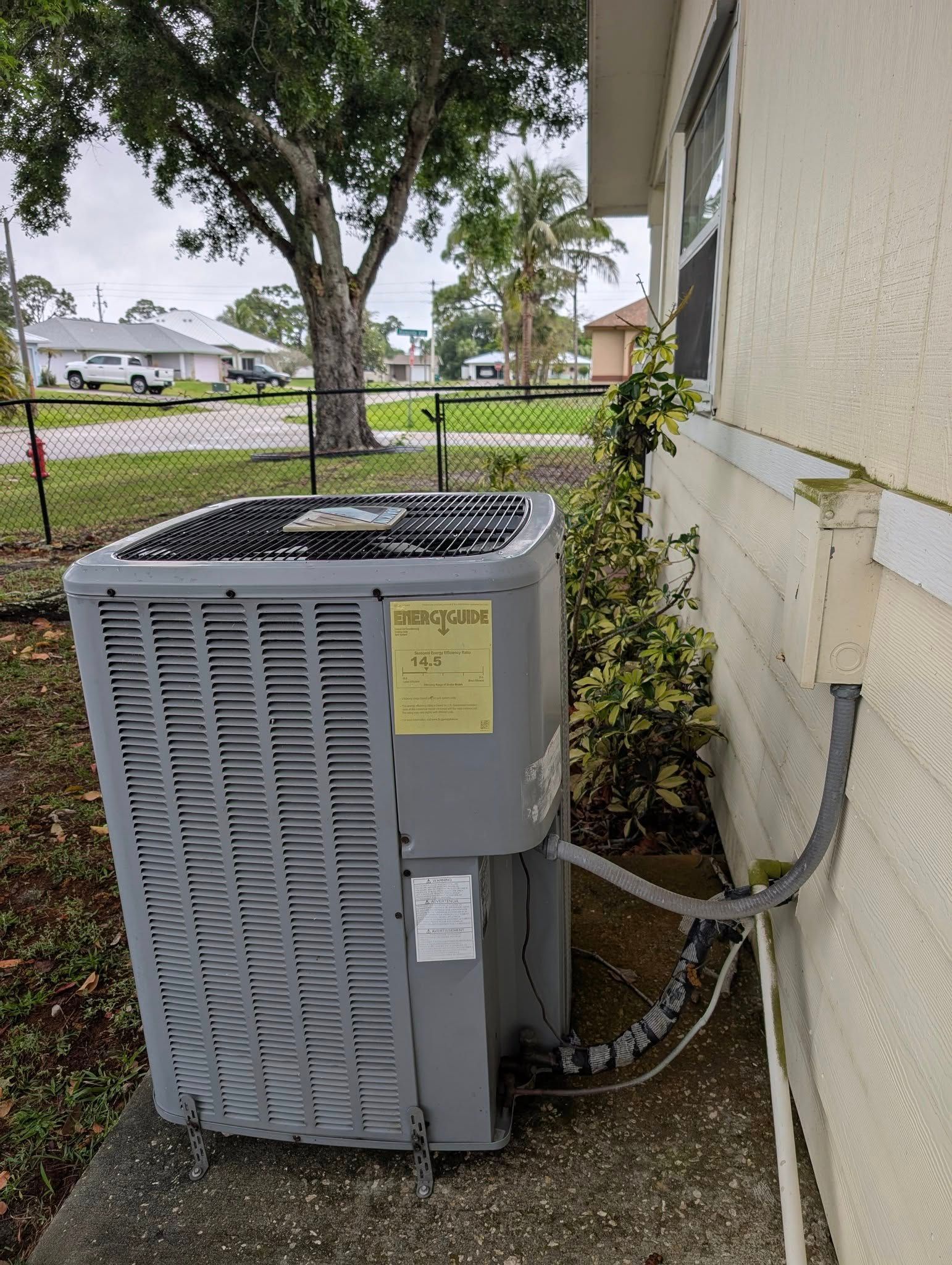An air conditioner is sitting on the side of a house next to a window.