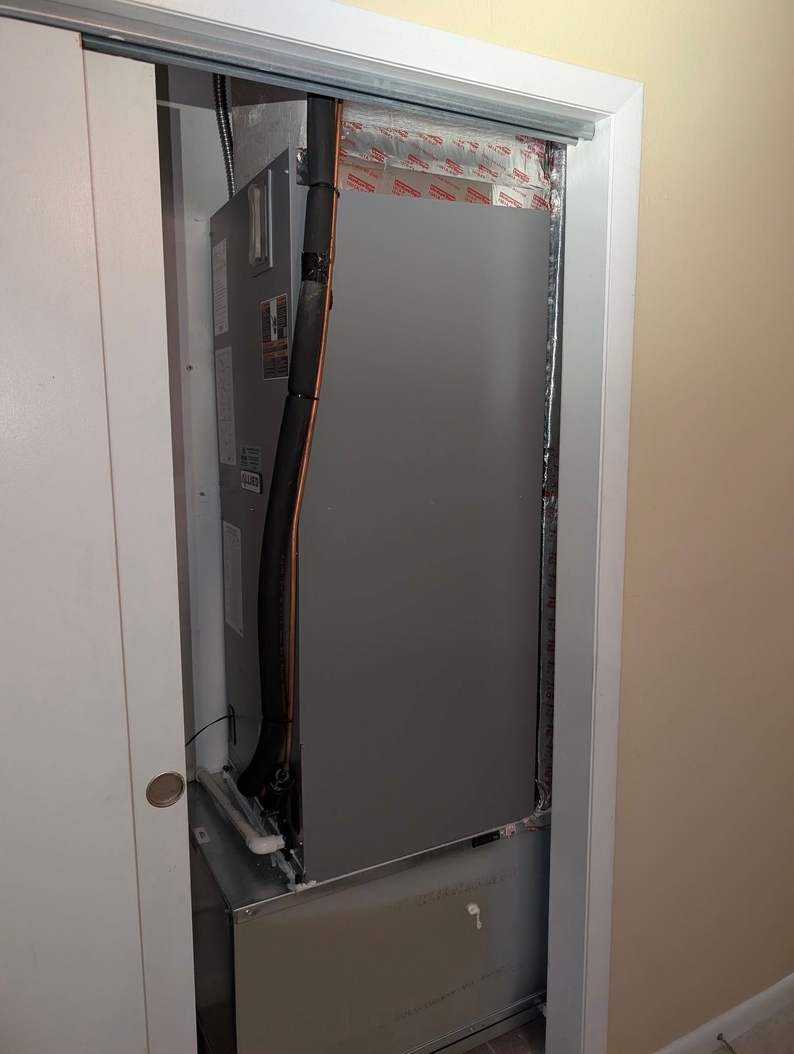 A refrigerator is sitting in a closet next to a door.