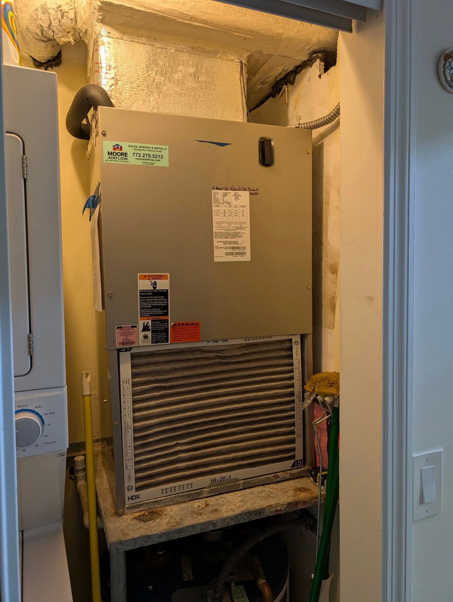 An air conditioner is sitting in a room next to a washer and dryer.