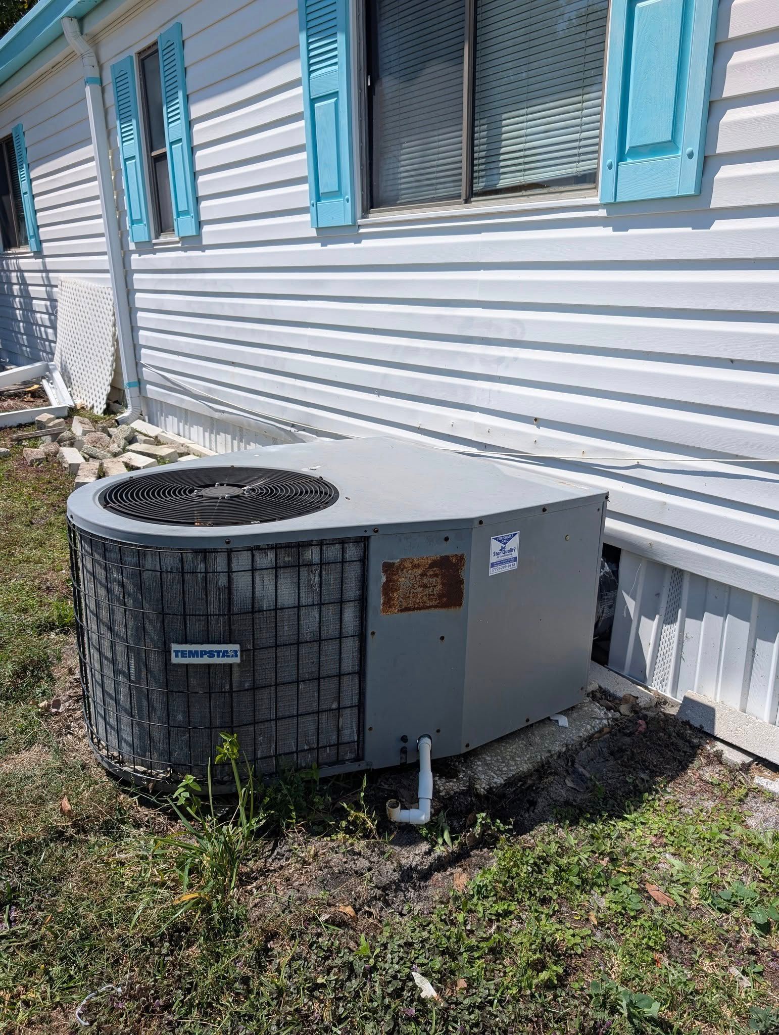 An air conditioner is sitting outside of a mobile home.