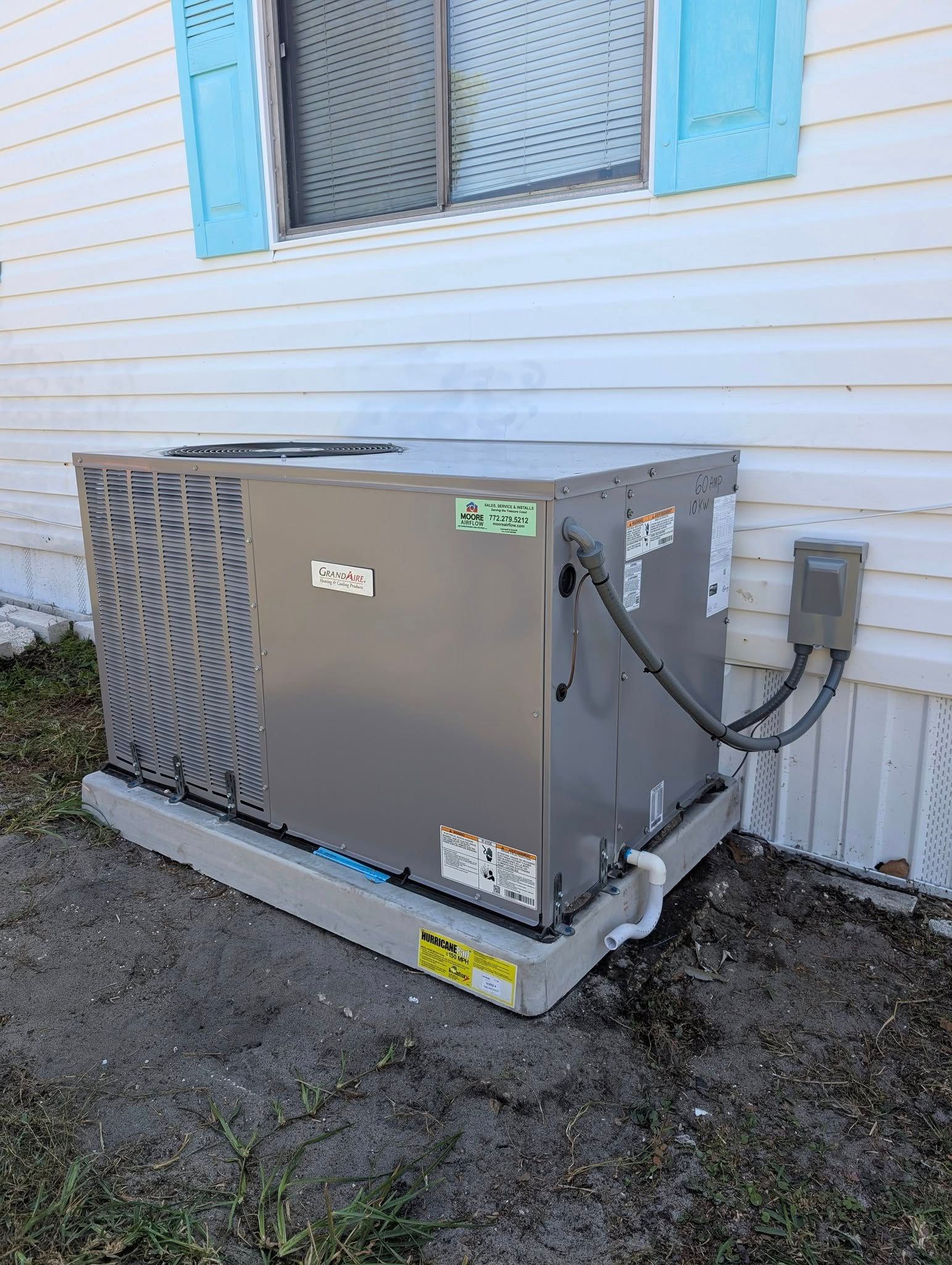 An air conditioner is sitting on the side of a house next to a window.