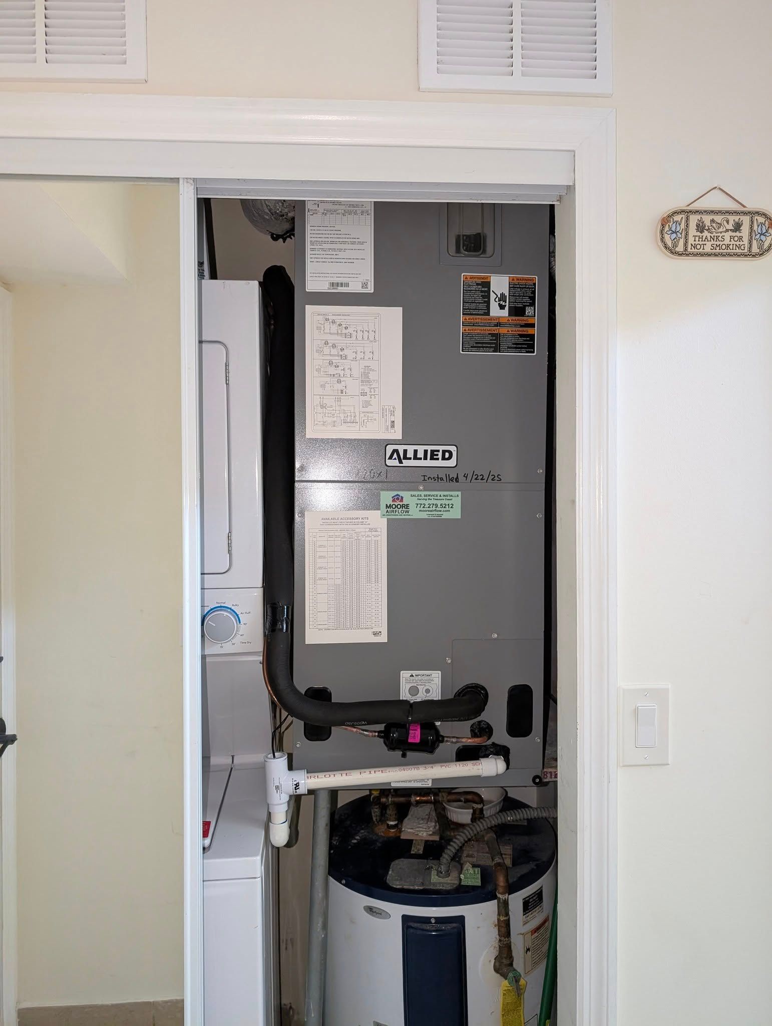 An air conditioner is sitting inside of a closet next to a water heater.