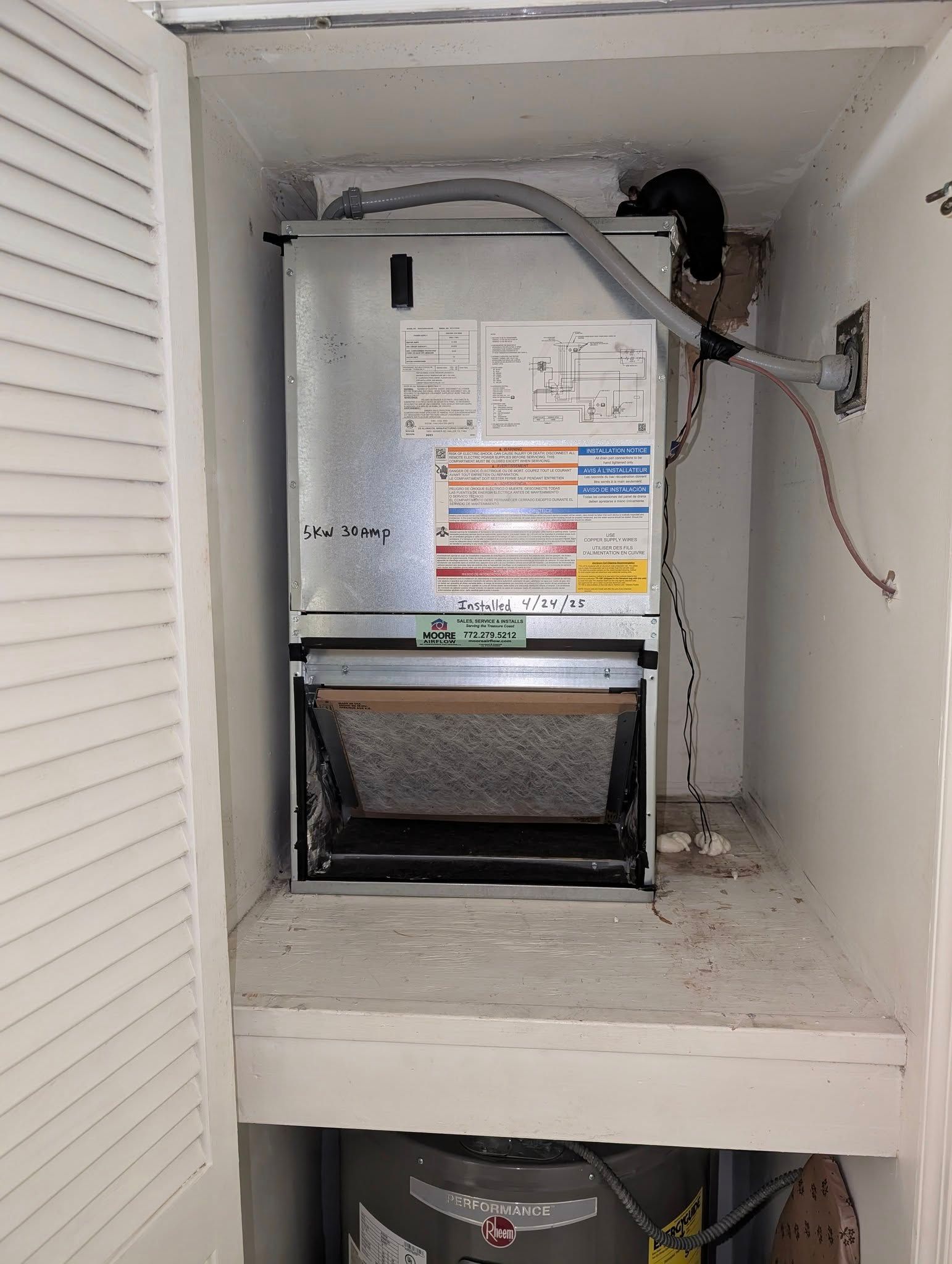 An air conditioner is sitting on top of a shelf in a closet.