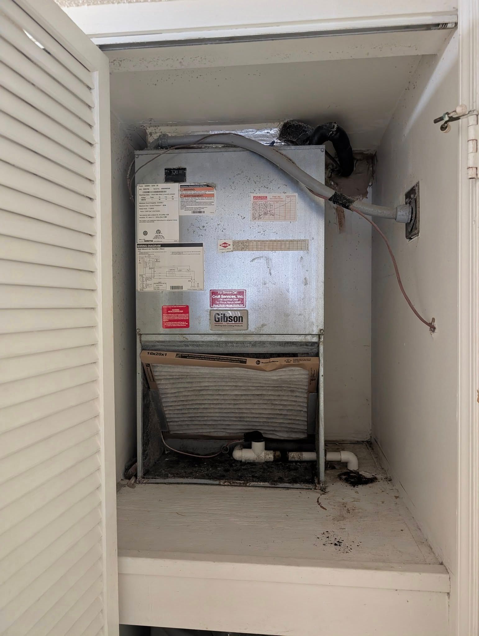 An air conditioner is sitting in a closet under a staircase.
