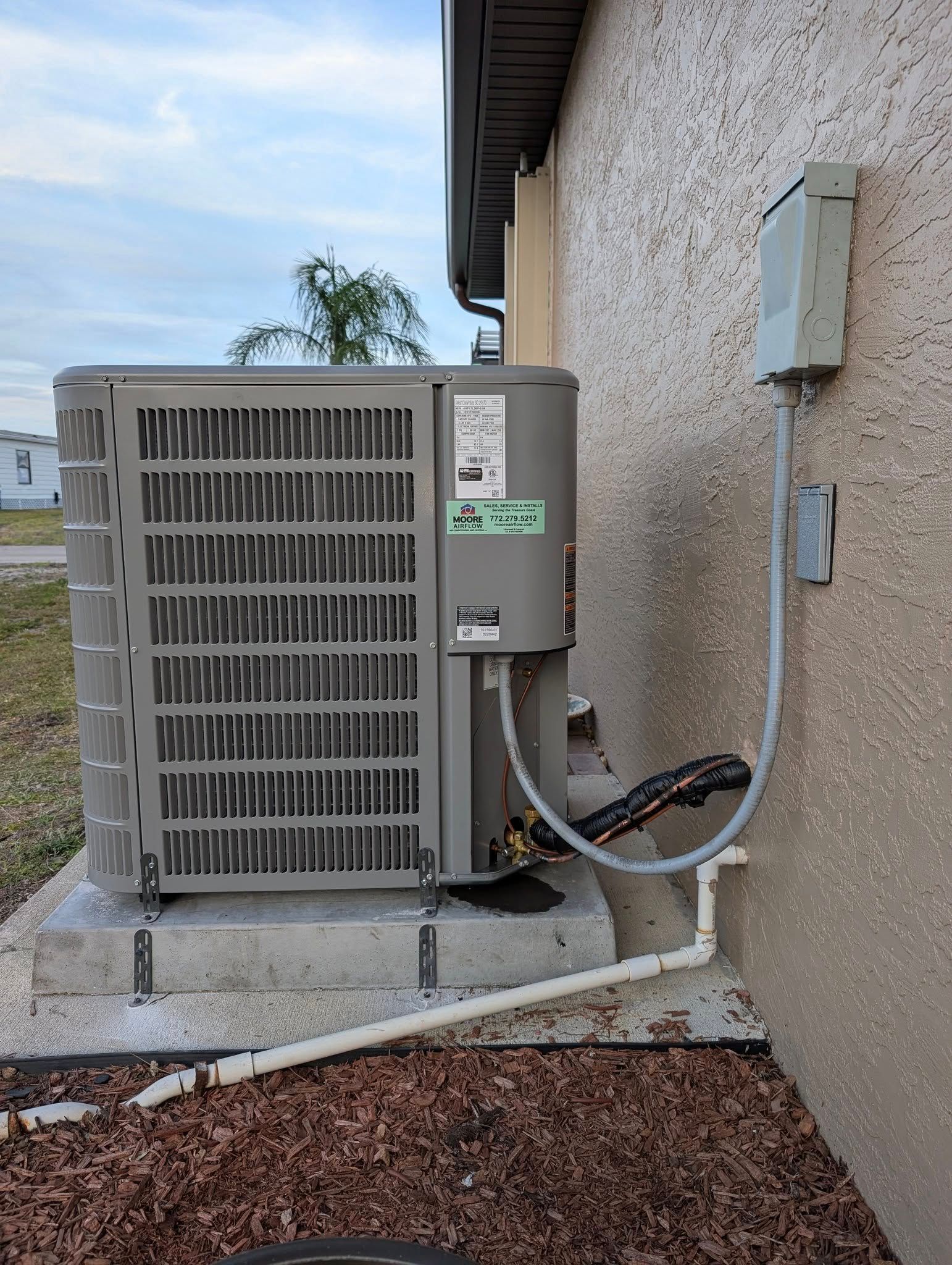 An air conditioner is attached to the side of a house.