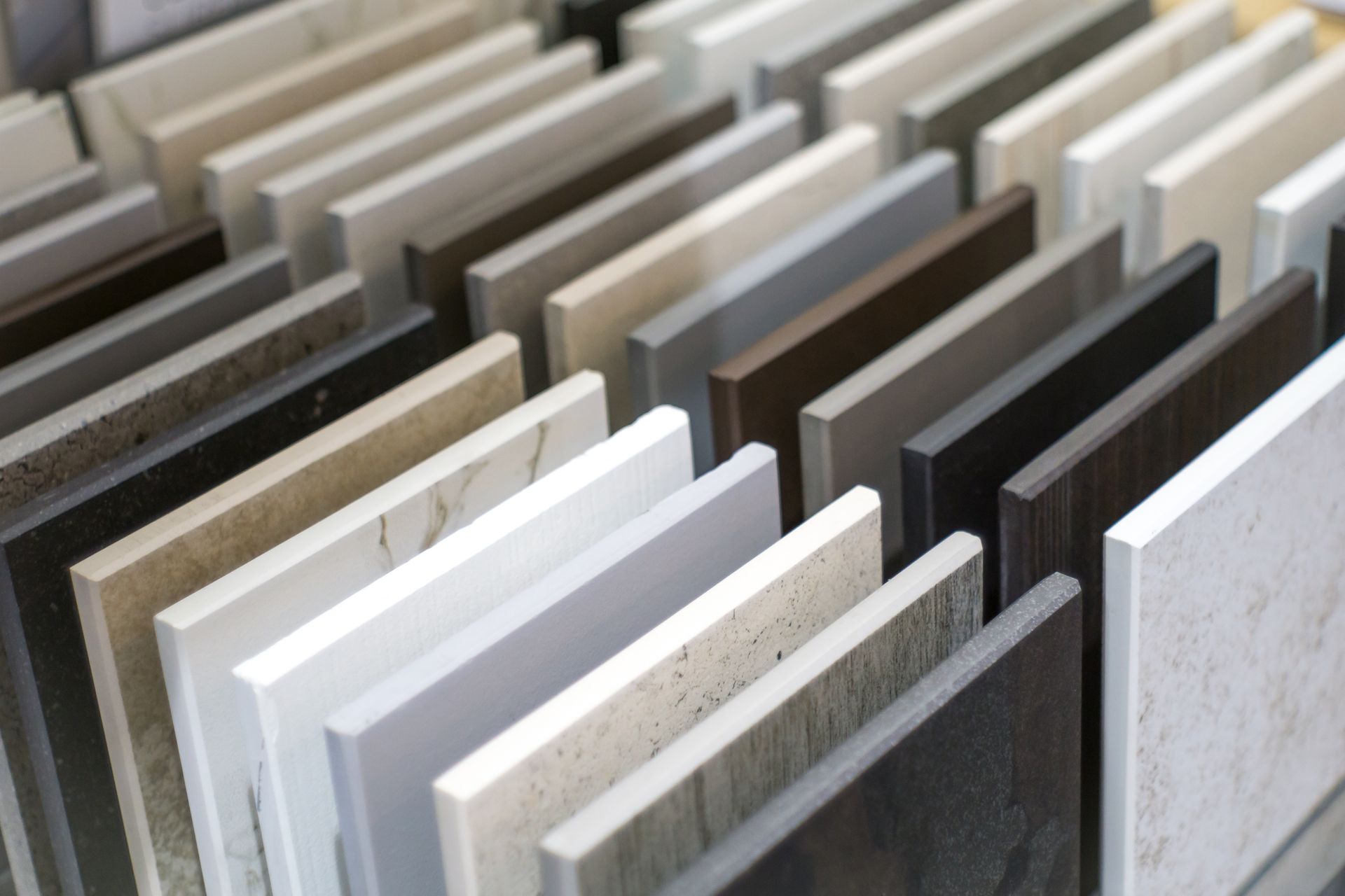Rows of ceramic and stone tile samples displayed vertically in a showroom.