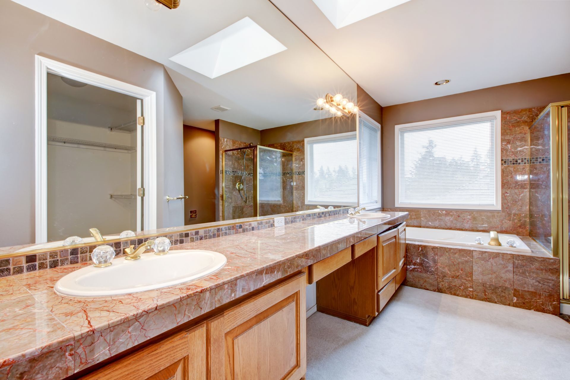 Bathroom with marble countertops, large mirror, tub, shower, and window.