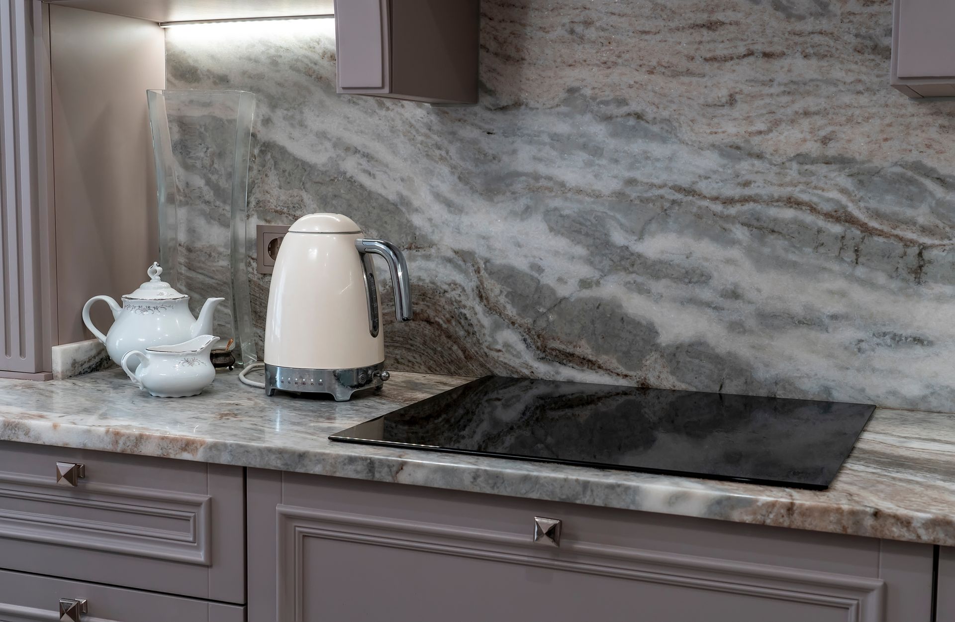 Modern kitchen countertop with marble backsplash and electric cooktop. Modern kitchen countertop with marble backsplash and electric cooktop.