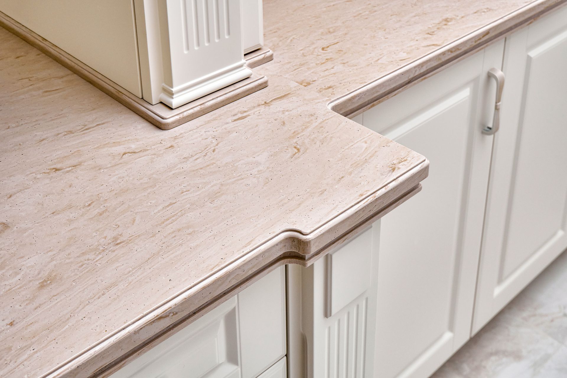 Beige countertop with decorative edge on white cabinets.
