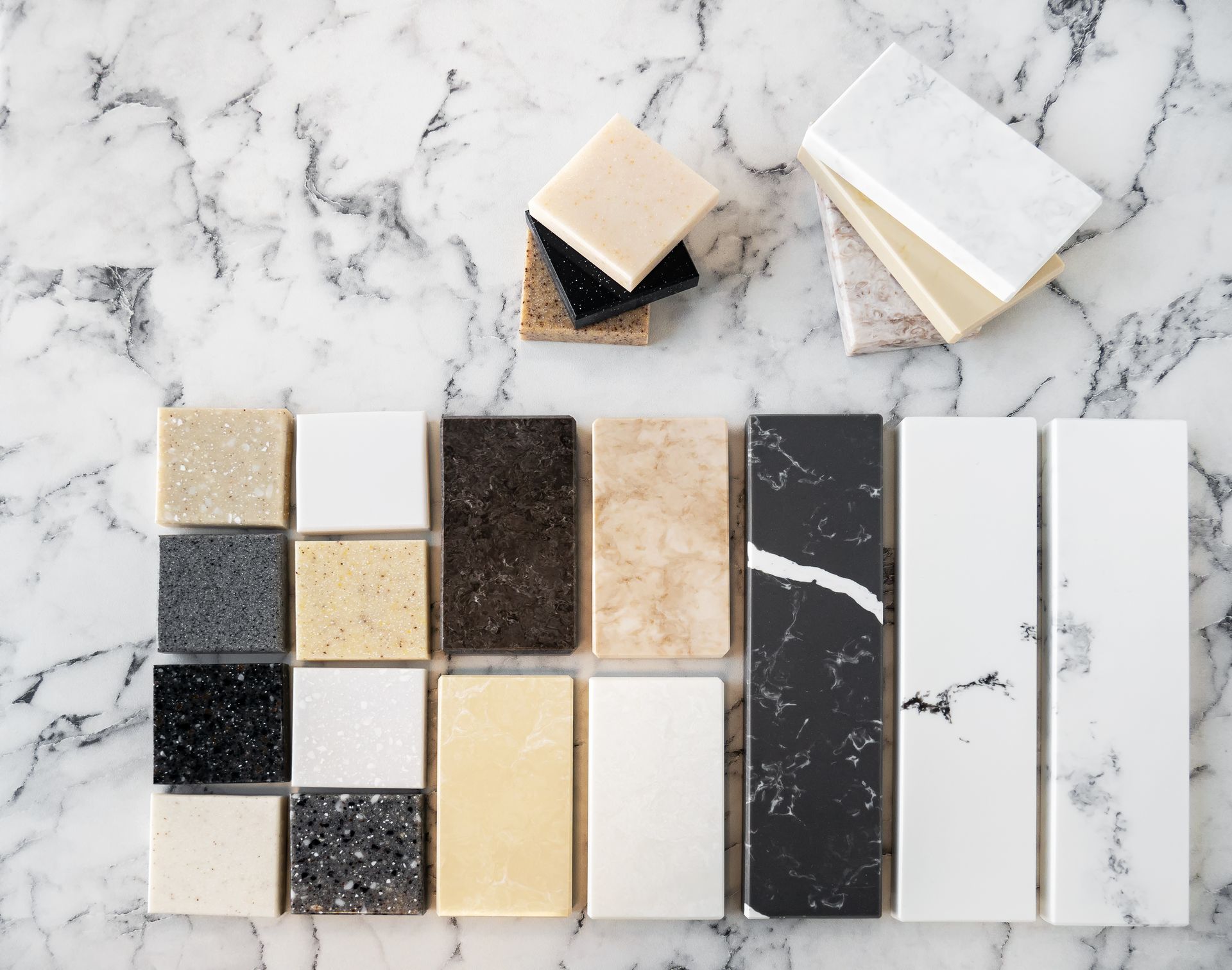 Samples of countertop materials in various colors and textures on a marble surface.