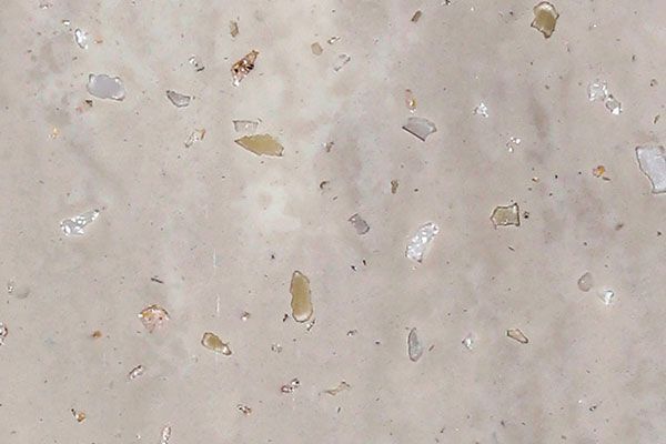 Beige stone surface with embedded chips of various colors.